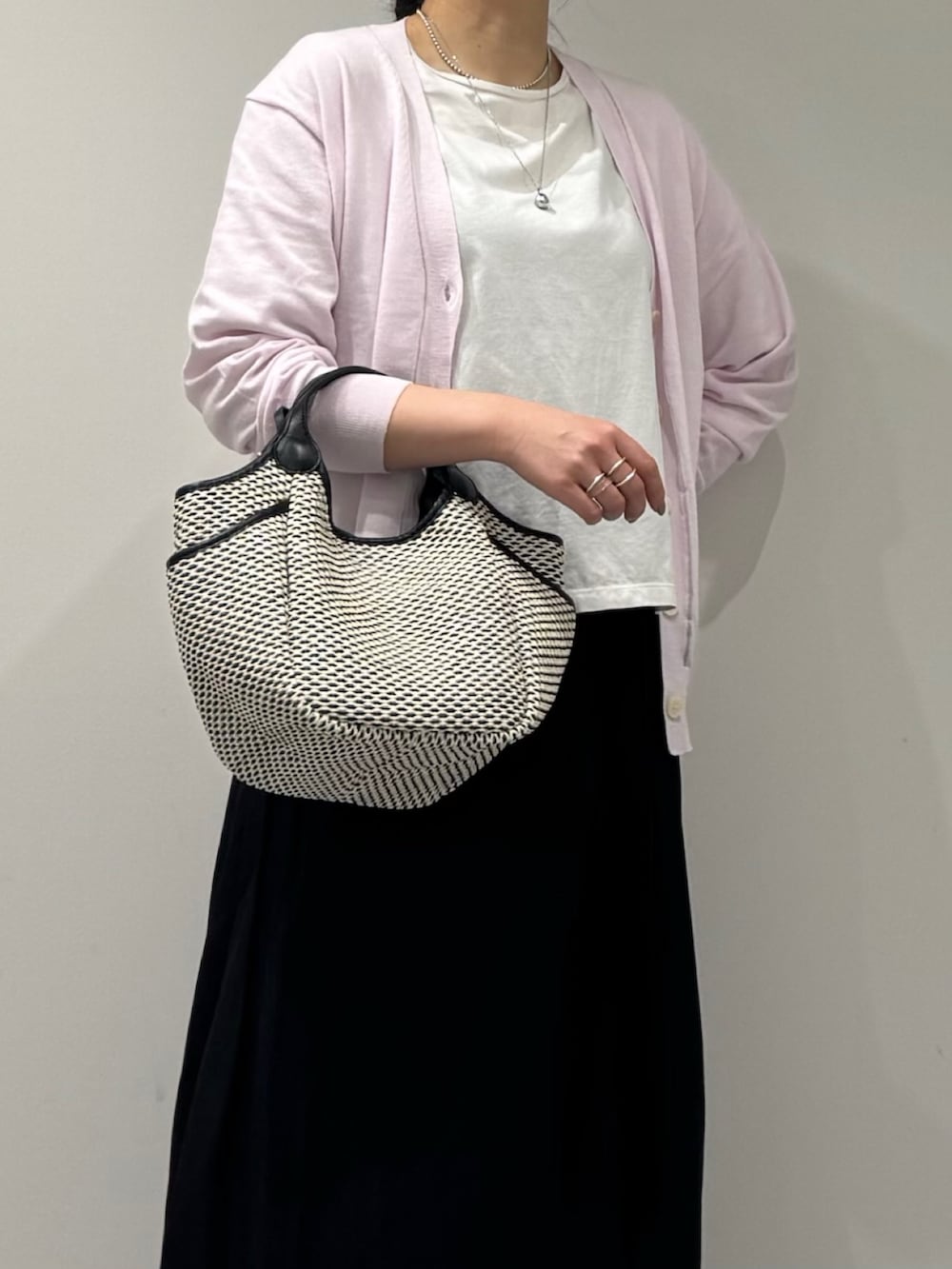 ブラック系のかごバッグ、ピンク系のカーディガン/ボレロ、ホワイト系のTシャツ/カットソーを着用したレディースの春コーディネートの6枚目の写真