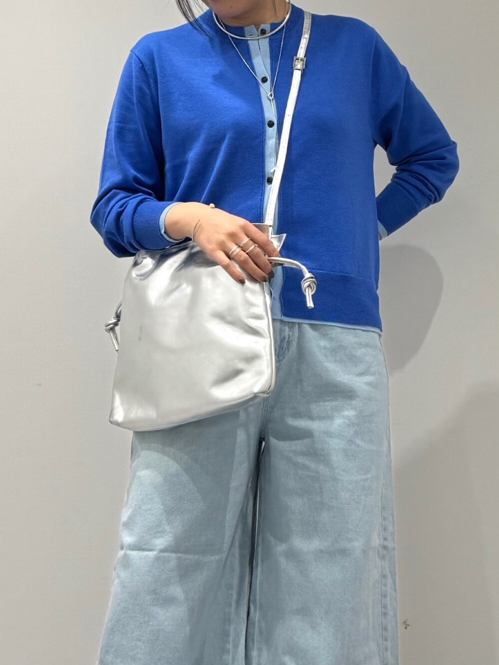 シルバー系のショルダーバッグ、ブルー系のカーディガン/ボレロ、ブルー系のデニムパンツを着用したレディースの冬コーディネートの8枚目の写真