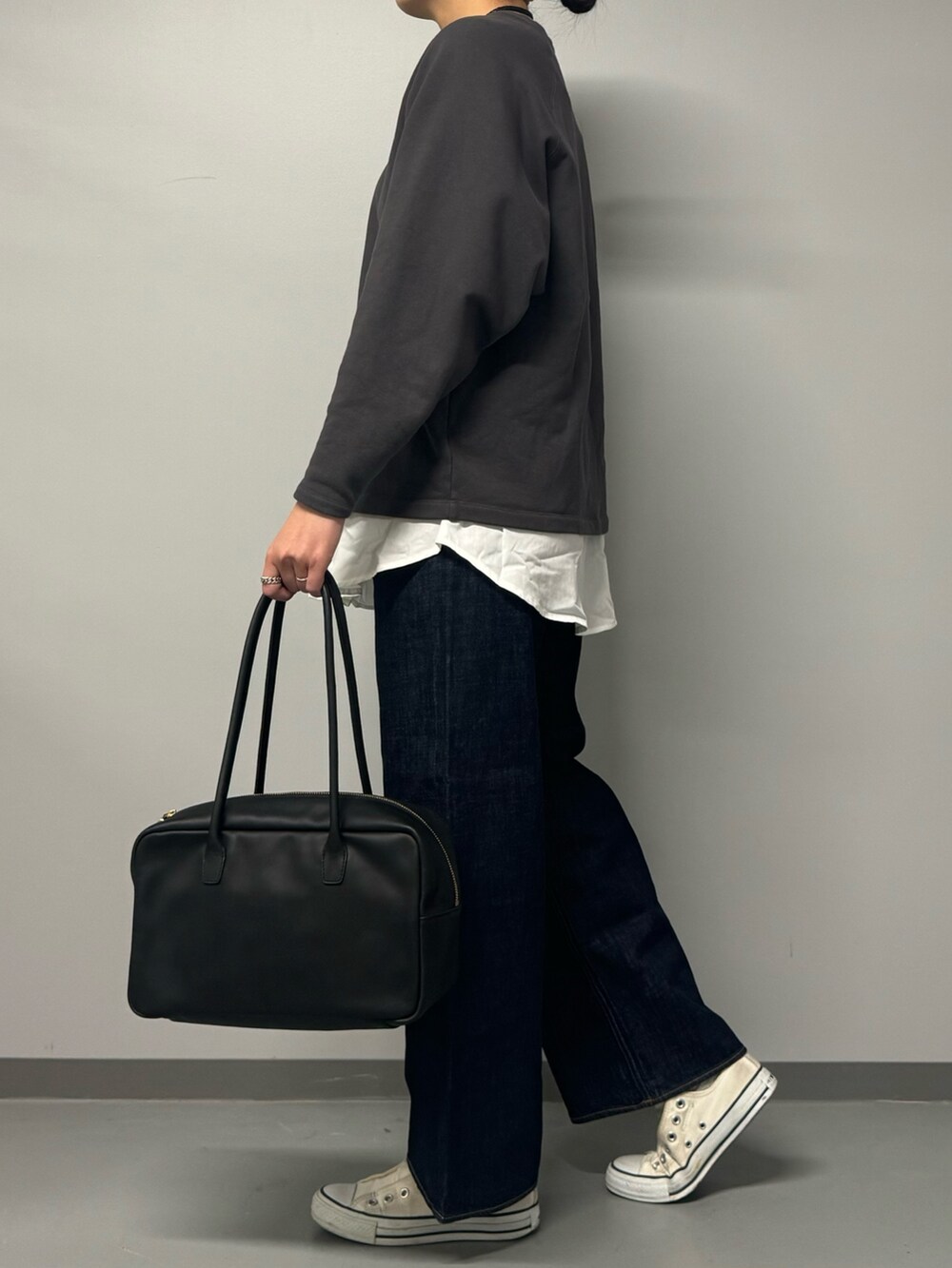 グレー系のスウェット、ブルー系のデニムパンツ、ブラック系のボストンバッグを着用したレディースの秋コーディネートの6枚目の写真
