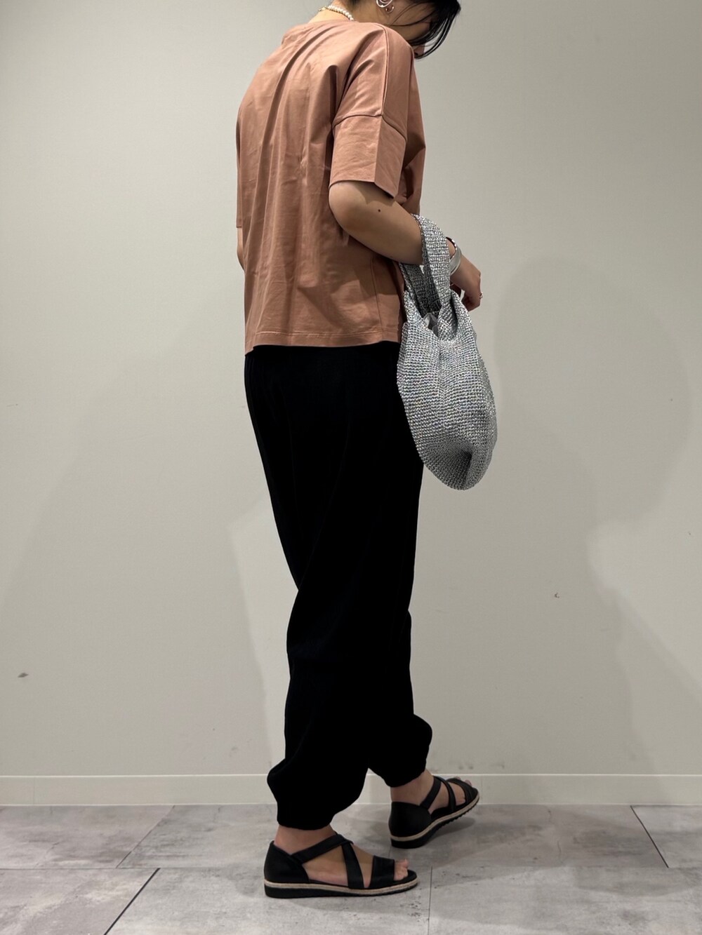 シルバー系のかごバッグ、ブラック系のサンダル、ゴールド系のネックレスを着用したレディースの春コーディネートの3枚目の写真