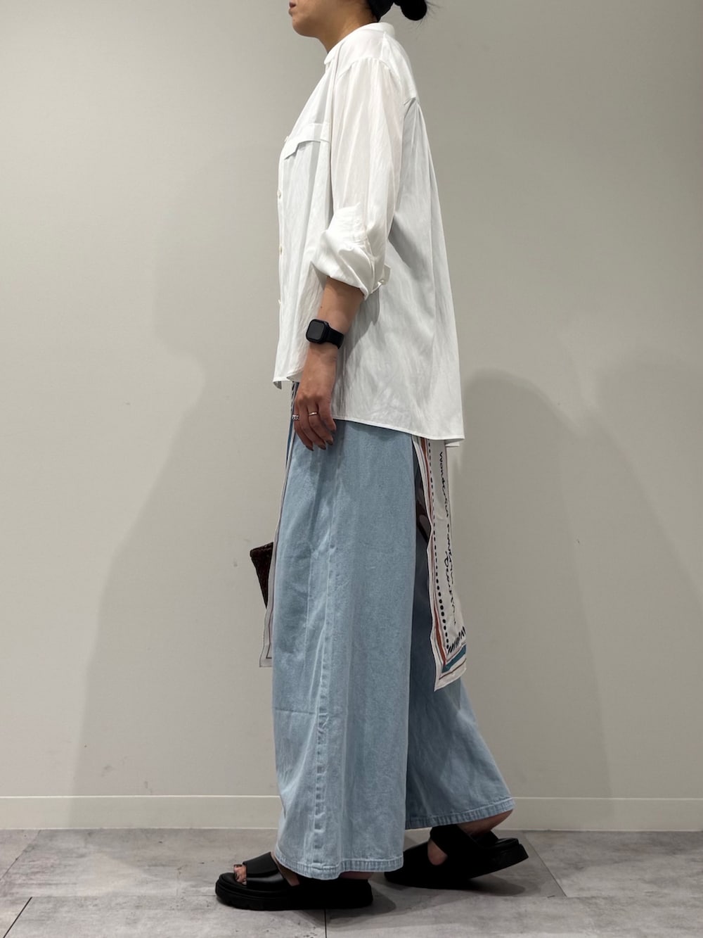 ブラウン系のトートバッグ、ブルー系のデニムパンツ、ブラック系のサンダルを着用したレディースの秋コーディネートの5枚目の写真