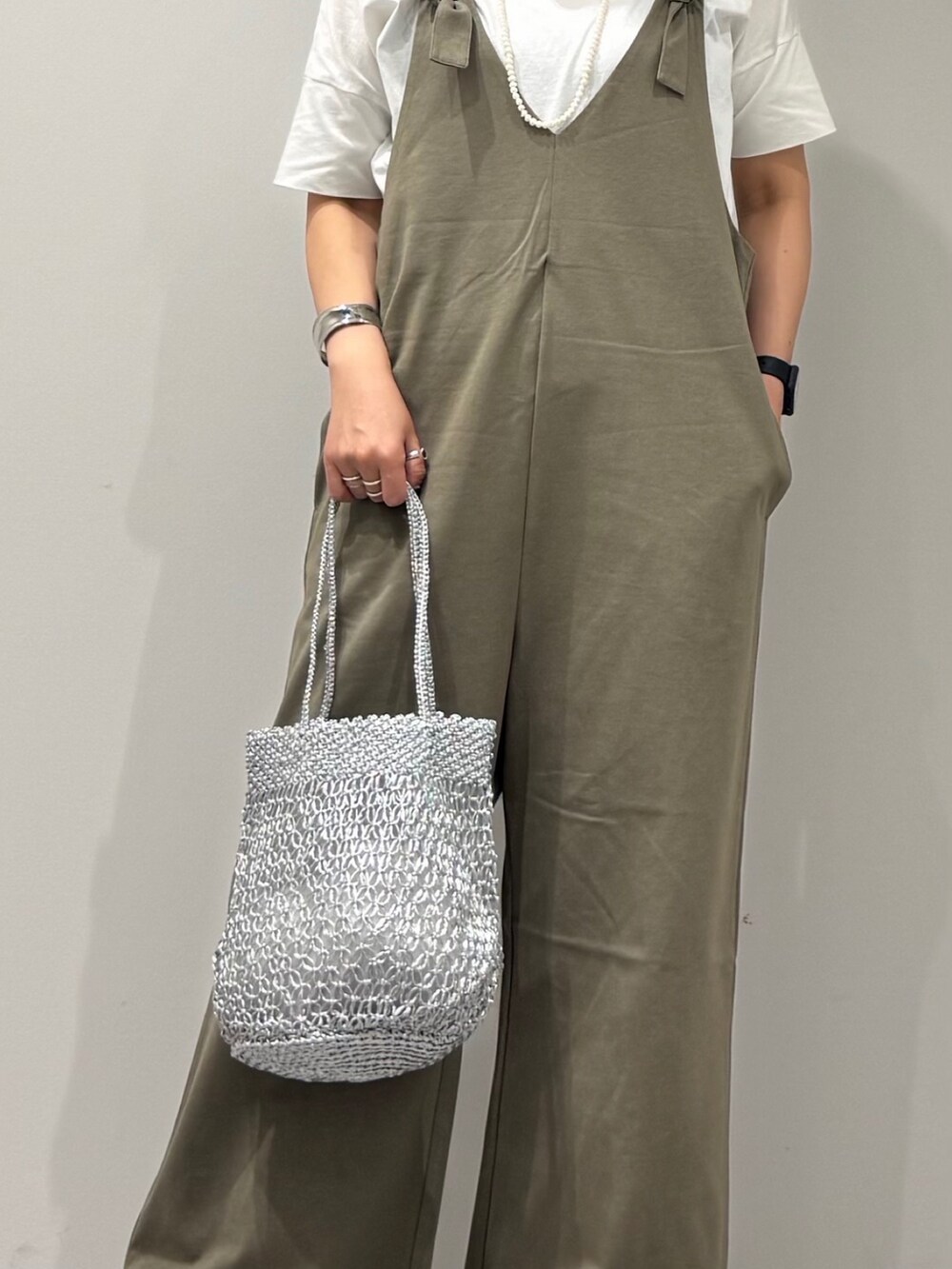 シルバー系のかごバッグ、ブラック系のサンダル、ホワイト系のTシャツ/カットソーを着用したレディースの夏コーディネートの8枚目の写真