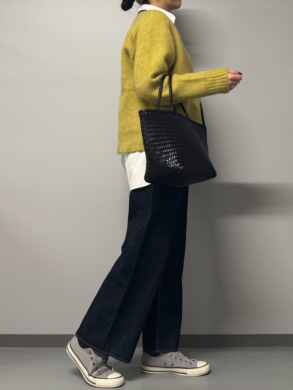 イエロー系のニット/セーター、ホワイト系のシャツ/ブラウス、ブルー系のデニムパンツを着用したレディースの冬コーディネートの3枚目の写真