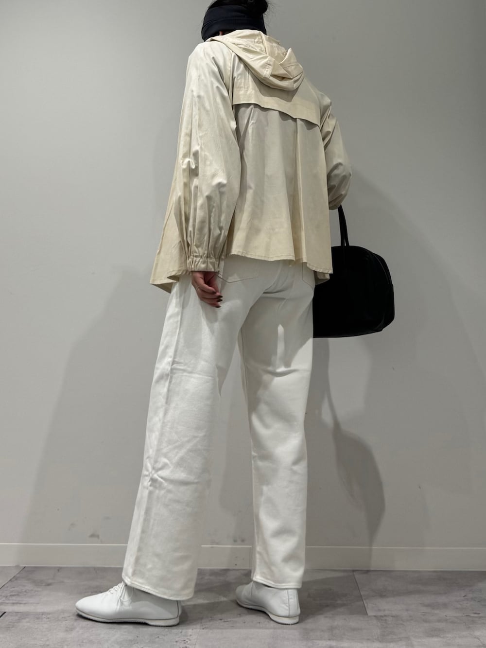 ブラック系のボストンバッグ、ホワイト系のトレンチコート、ホワイト系のデニムパンツを着用したレディースの冬コーディネートの4枚目の写真