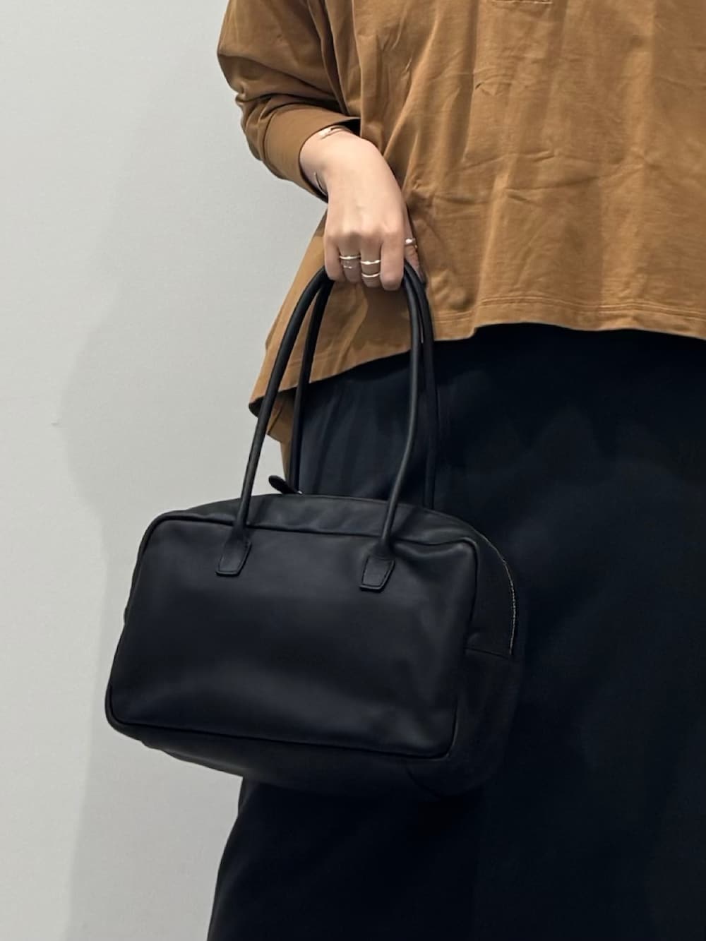 ブラック系のボストンバッグ、ベージュ系のTシャツ/カットソー、シルバー系のネックレスを着用したレディースの冬コーディネートの9枚目の写真