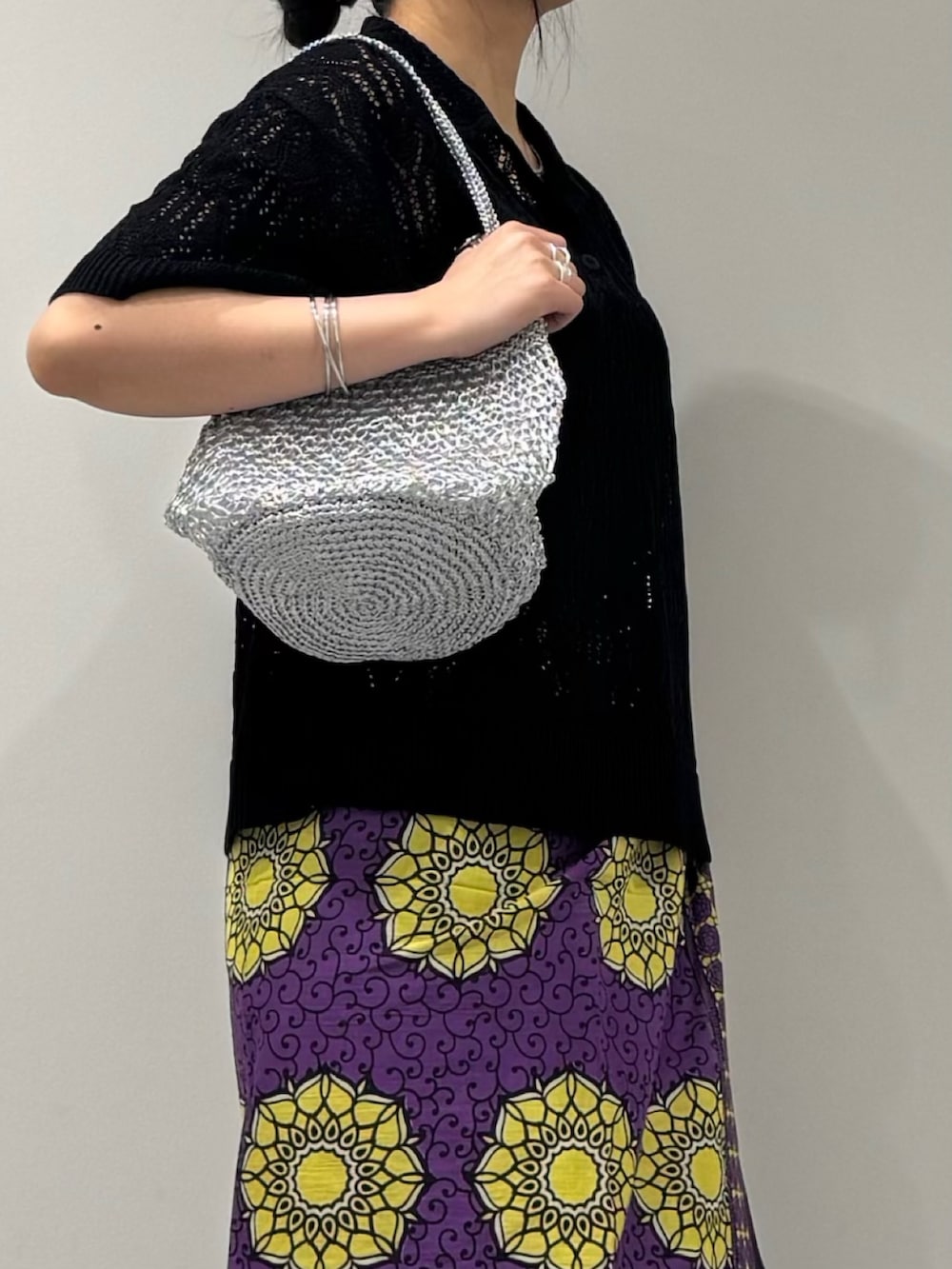 シルバー系のかごバッグ、グレー系のデニムパンツ、ブラック系のサンダルを着用したレディースの春コーディネートの7枚目の写真