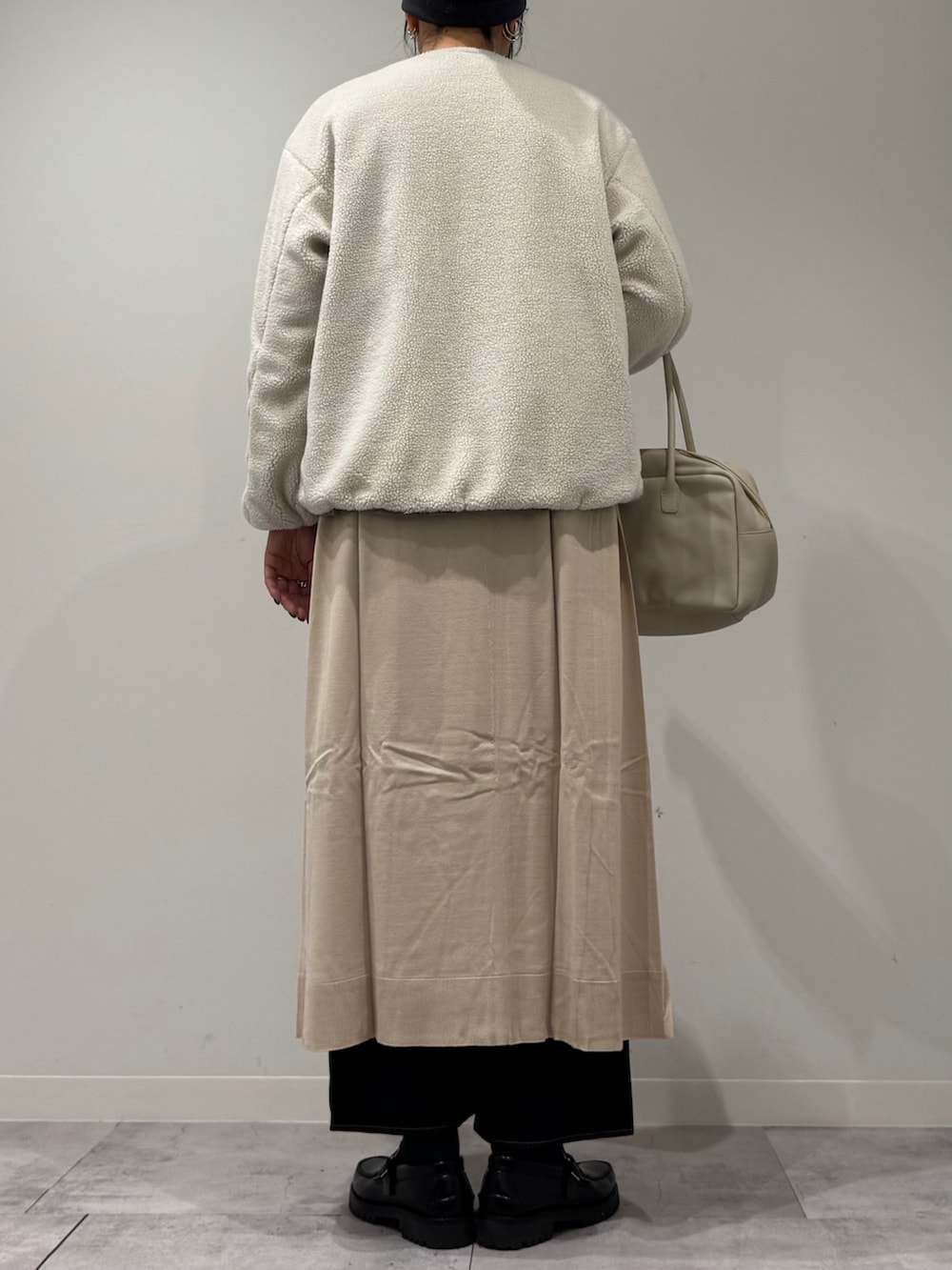 ベージュ系のボストンバッグ、ベージュ系のワンピース、ブルー系のデニムパンツを着用したレディースの春コーディネートの5枚目の写真