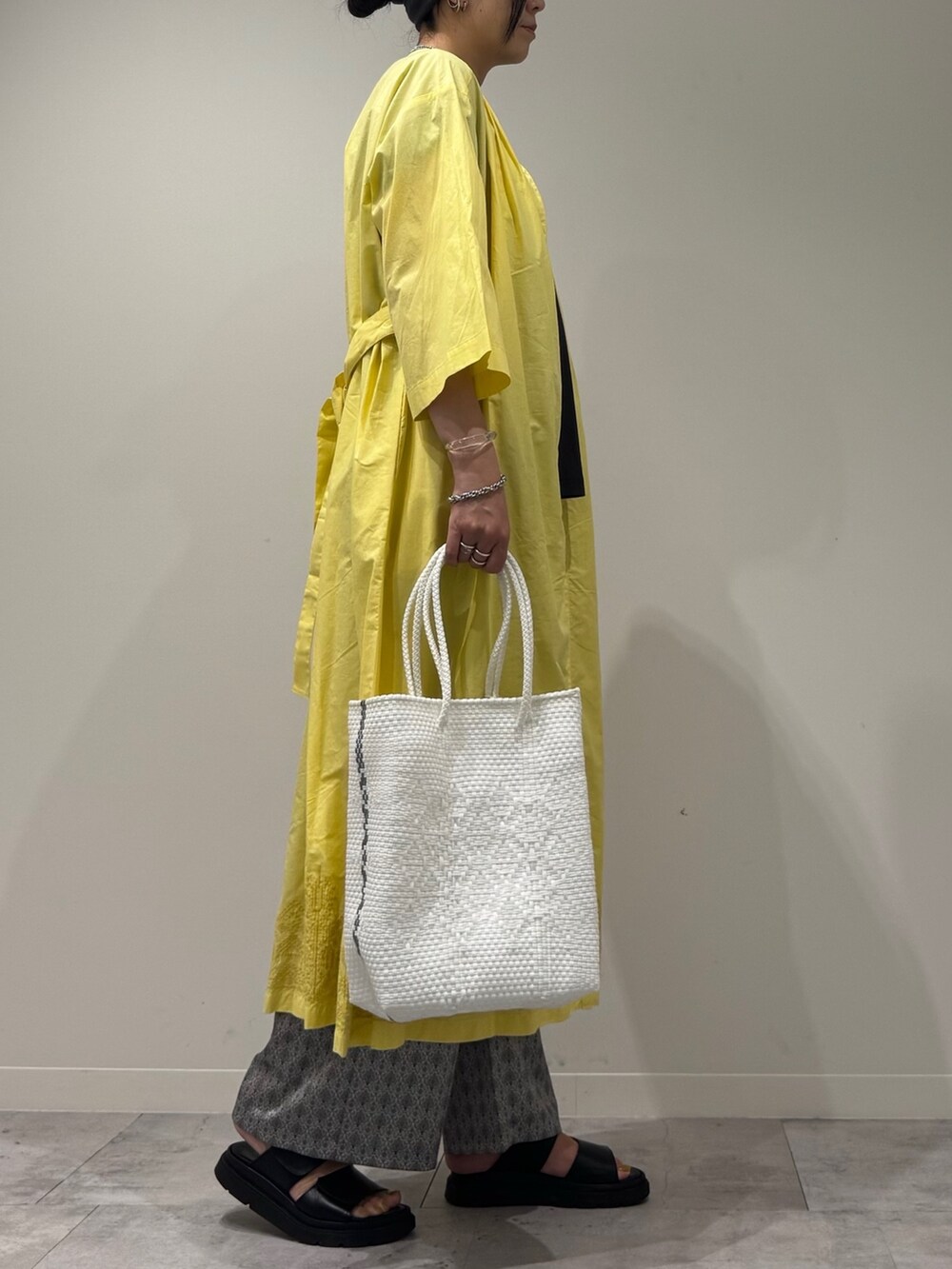 ホワイト系のかごバッグ、イエロー系のワンピース、ベージュ系のその他パンツを着用したレディースの夏コーディネートの3枚目の写真