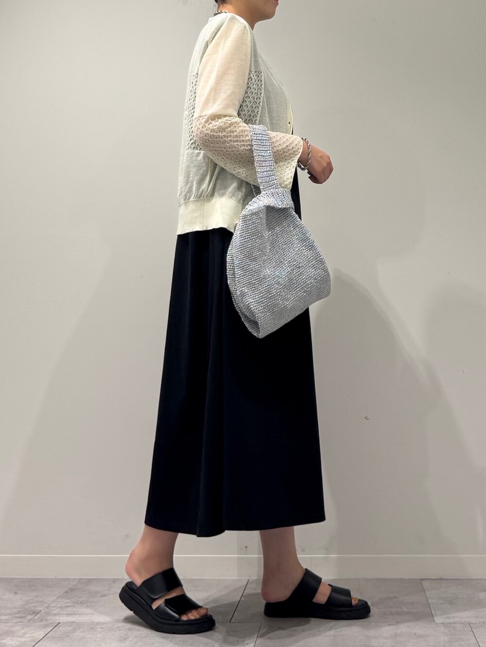 シルバー系のかごバッグ、ブラック系のワンピース、ホワイト系のカーディガン/ボレロを着用したレディースの秋コーディネートの3枚目の写真