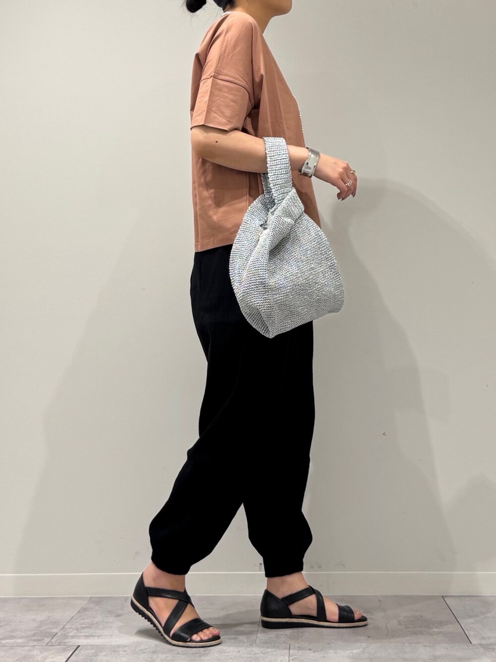 シルバー系のかごバッグ、ブラック系のサンダル、ゴールド系のネックレスを着用したレディースの春コーディネートの2枚目の写真