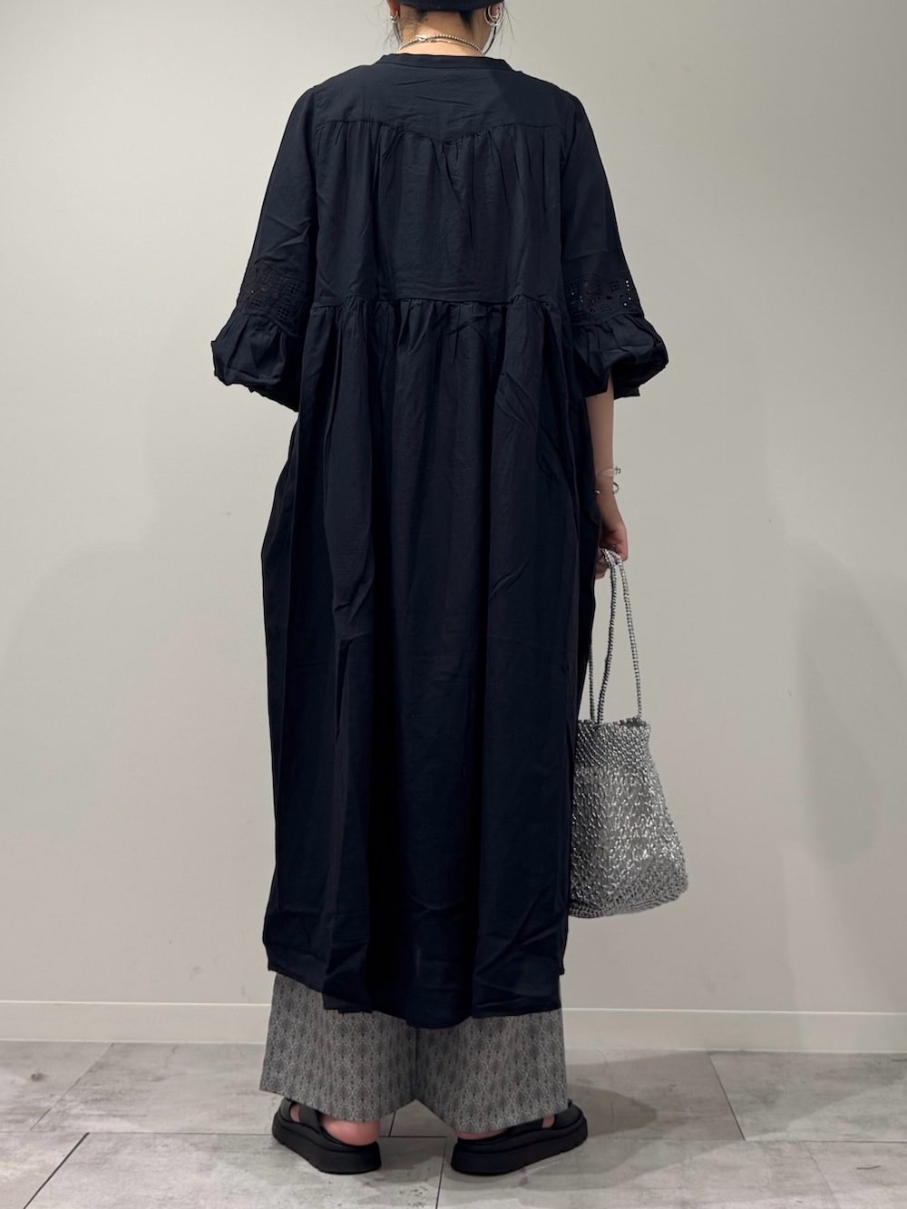 ブラック系のワンピース、シルバー系のかごバッグ、ブラック系のサンダルを着用したレディースの秋コーディネートの4枚目の写真