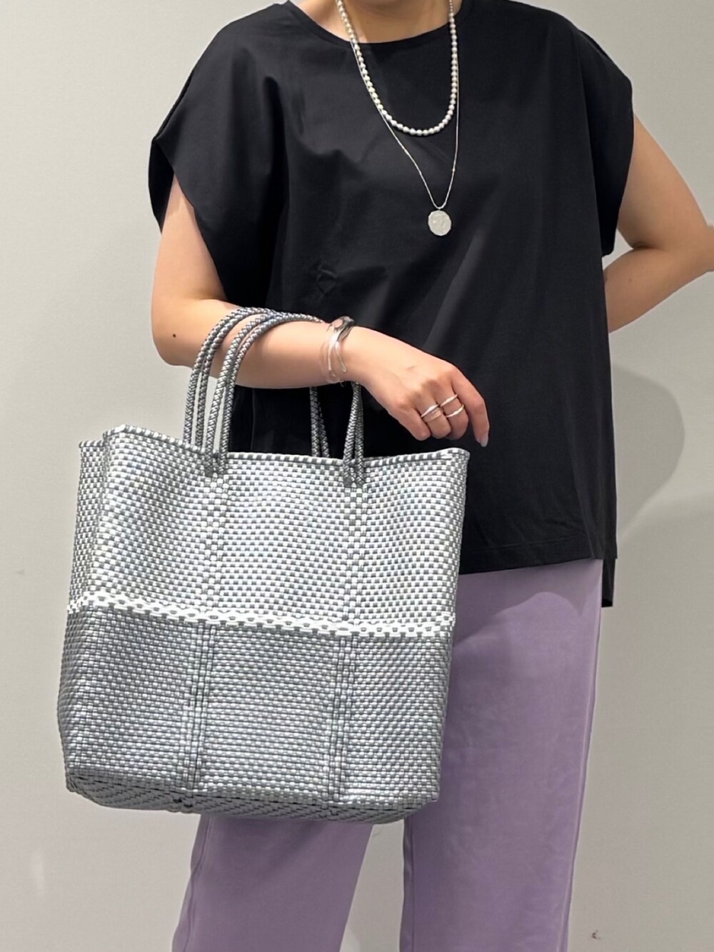 グレー系のTシャツ/カットソー、シルバー系のかごバッグ、ブラック系のサンダルを着用したレディースの夏コーディネートの9枚目の写真