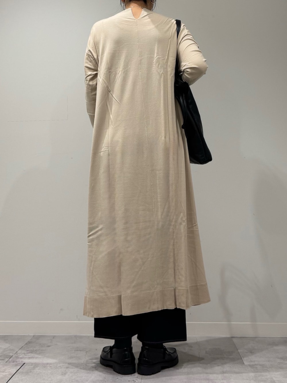 ベージュ系のワンピース、ブラック系のローファー、ブルー系のデニムパンツを着用したレディースの冬コーディネートの3枚目の写真