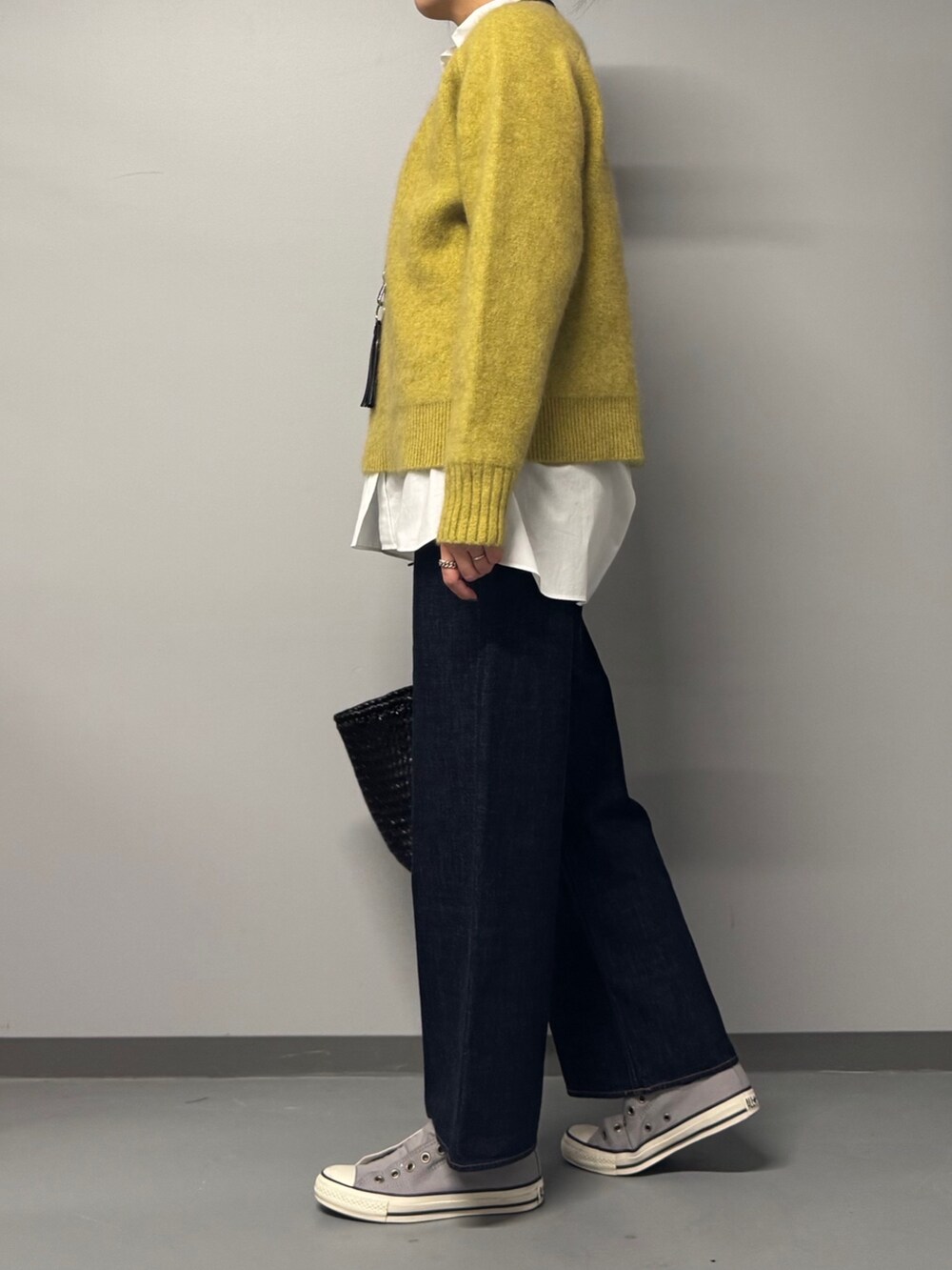 イエロー系のニット/セーター、ホワイト系のシャツ/ブラウス、ブルー系のデニムパンツを着用したレディースの冬コーディネートの5枚目の写真