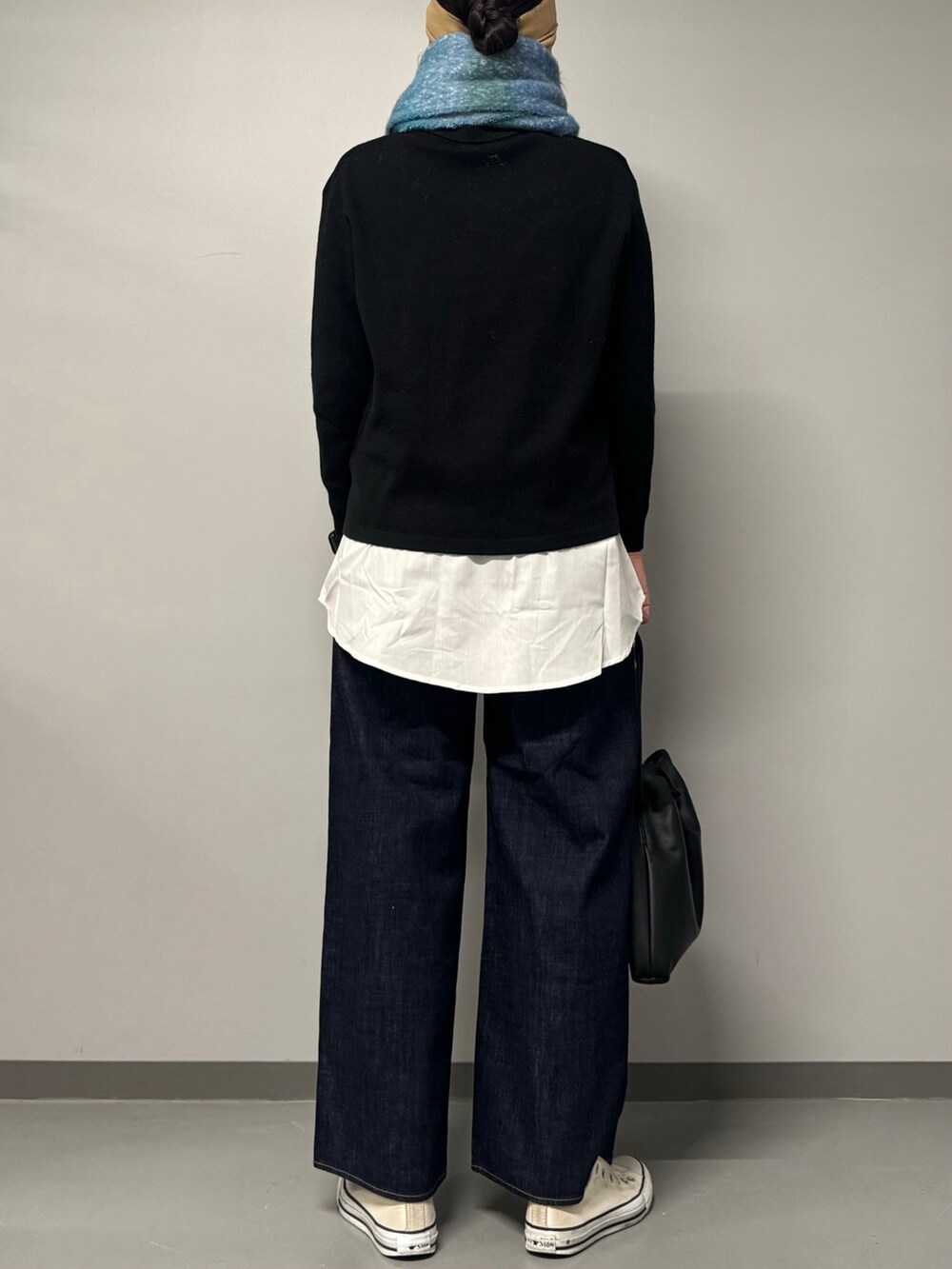 ブラック系のニット/セーター、ブルー系のデニムパンツ、ブラック系のショルダーバッグを着用したレディースの秋コーディネートの3枚目の写真