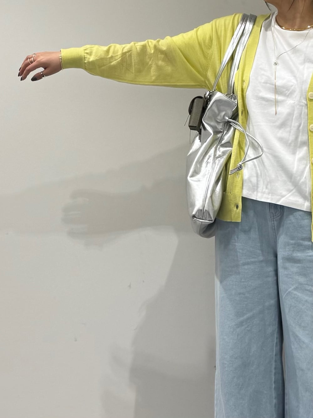 シルバー系のトートバッグ、ブラック系のローファー、ブルー系のデニムパンツを着用したレディースの春コーディネートの6枚目の写真