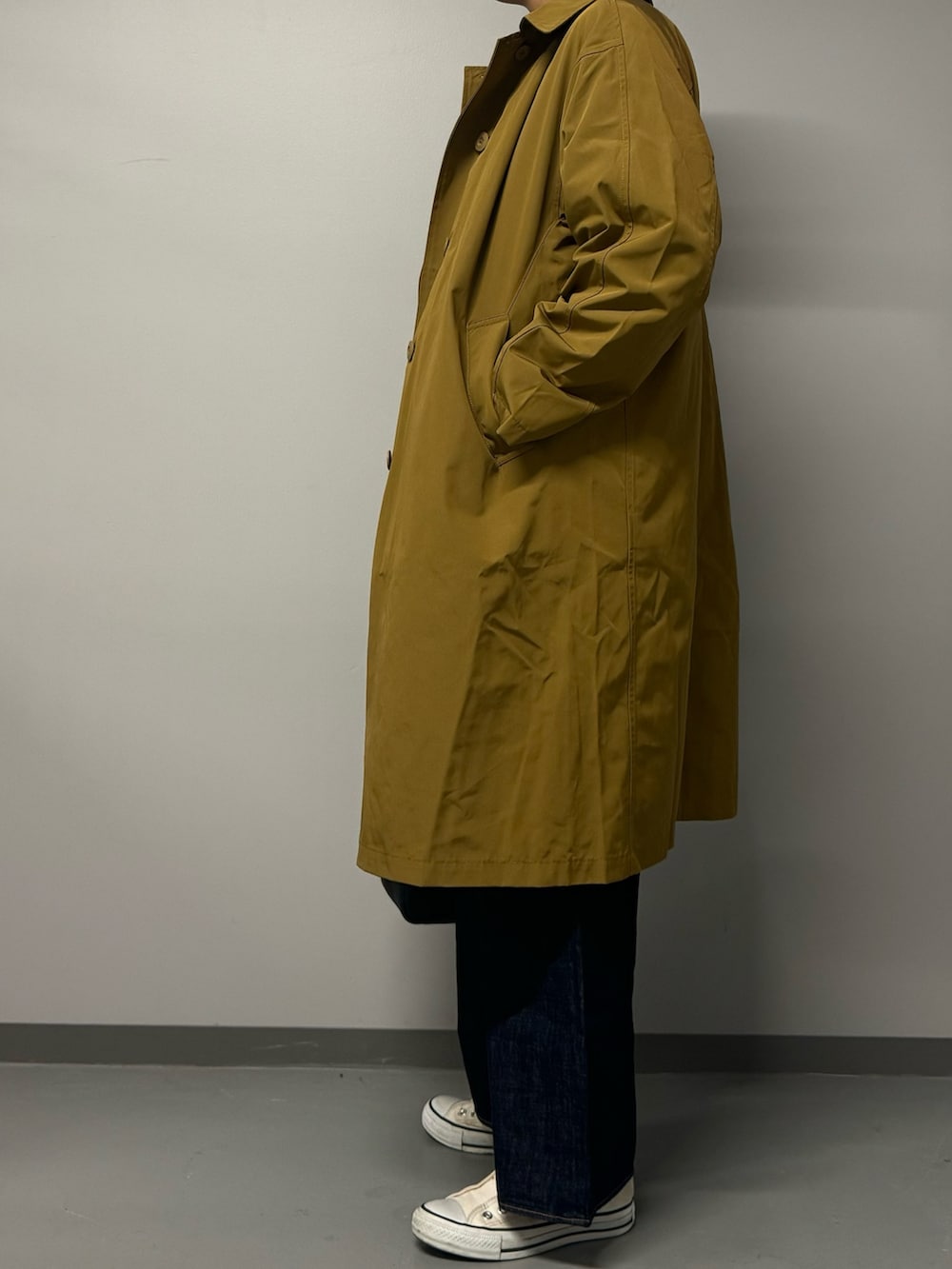 ベージュ系のダウンジャケット/コート、ブラック系のボストンバッグ、ブルー系のデニムパンツを着用したレディースの秋コーディネートの4枚目の写真