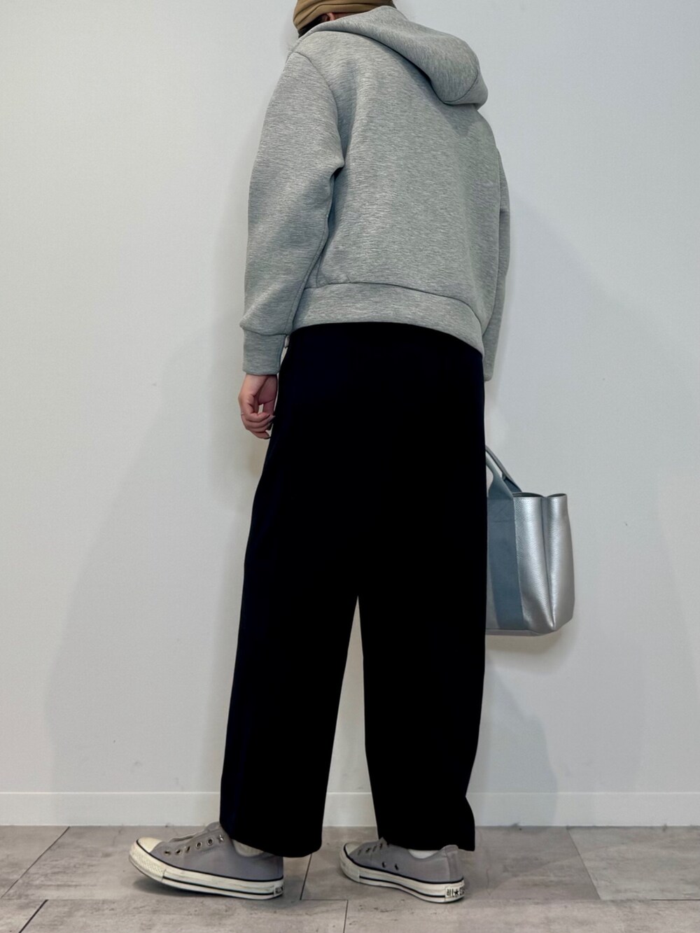 シルバー系のトートバッグ、ブラック系のサロペット/オーバーオール、グレー系のパーカーを着用したレディースの冬コーディネートの4枚目の写真