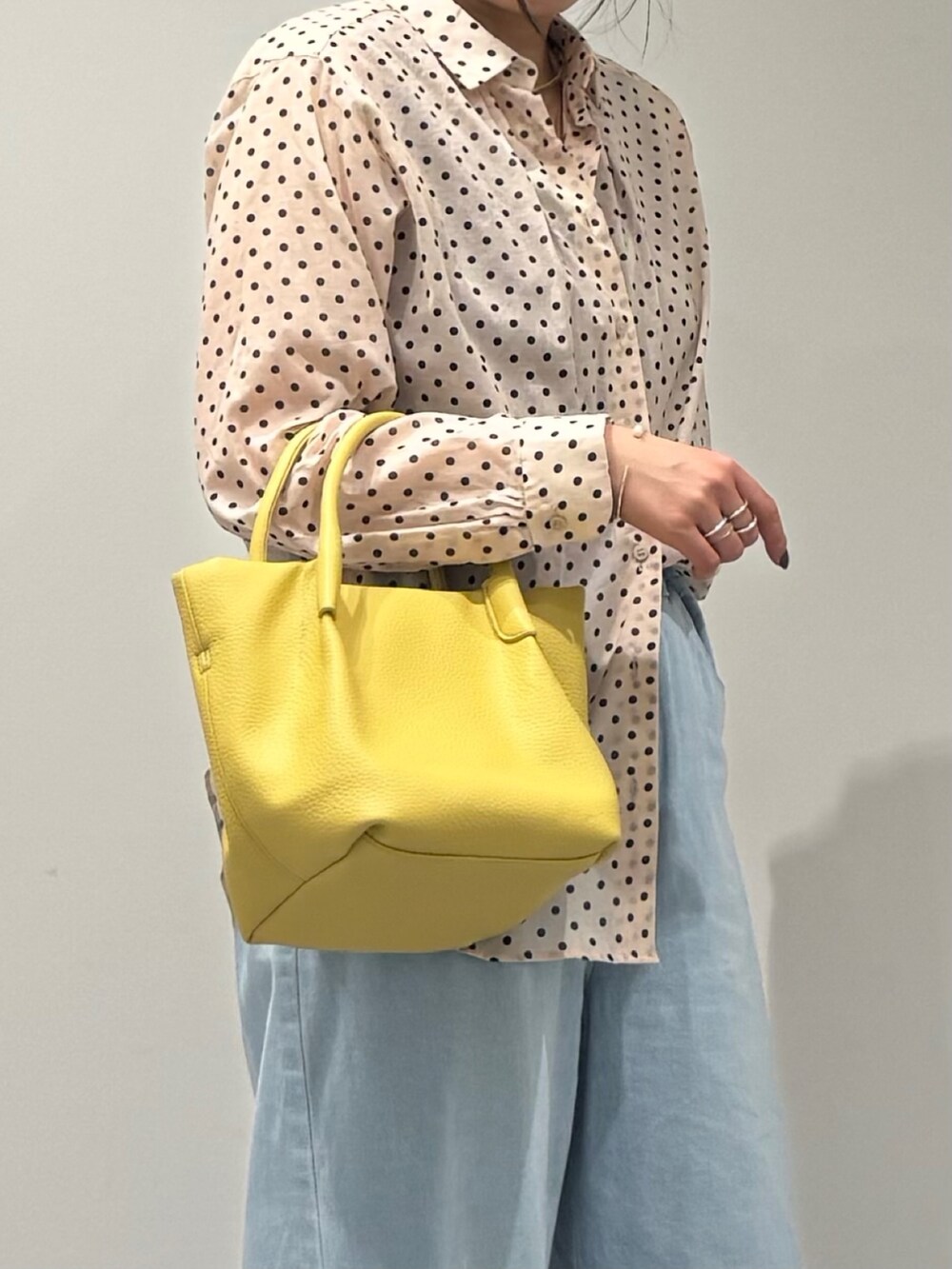 イエロー系のショルダーバッグ、ブルー系のデニムパンツ、ブラック系のローファーを着用したレディースの春コーディネートの7枚目の写真