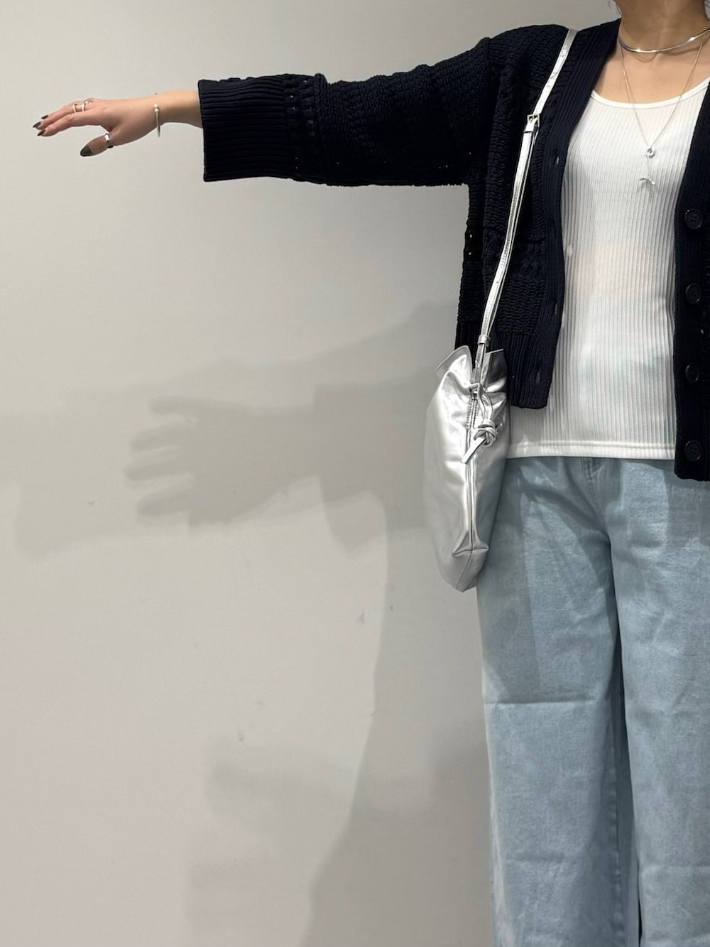 シルバー系のショルダーバッグ、ブルー系のデニムパンツ、ホワイト系のタンクトップを着用したレディースの春コーディネートの6枚目の写真