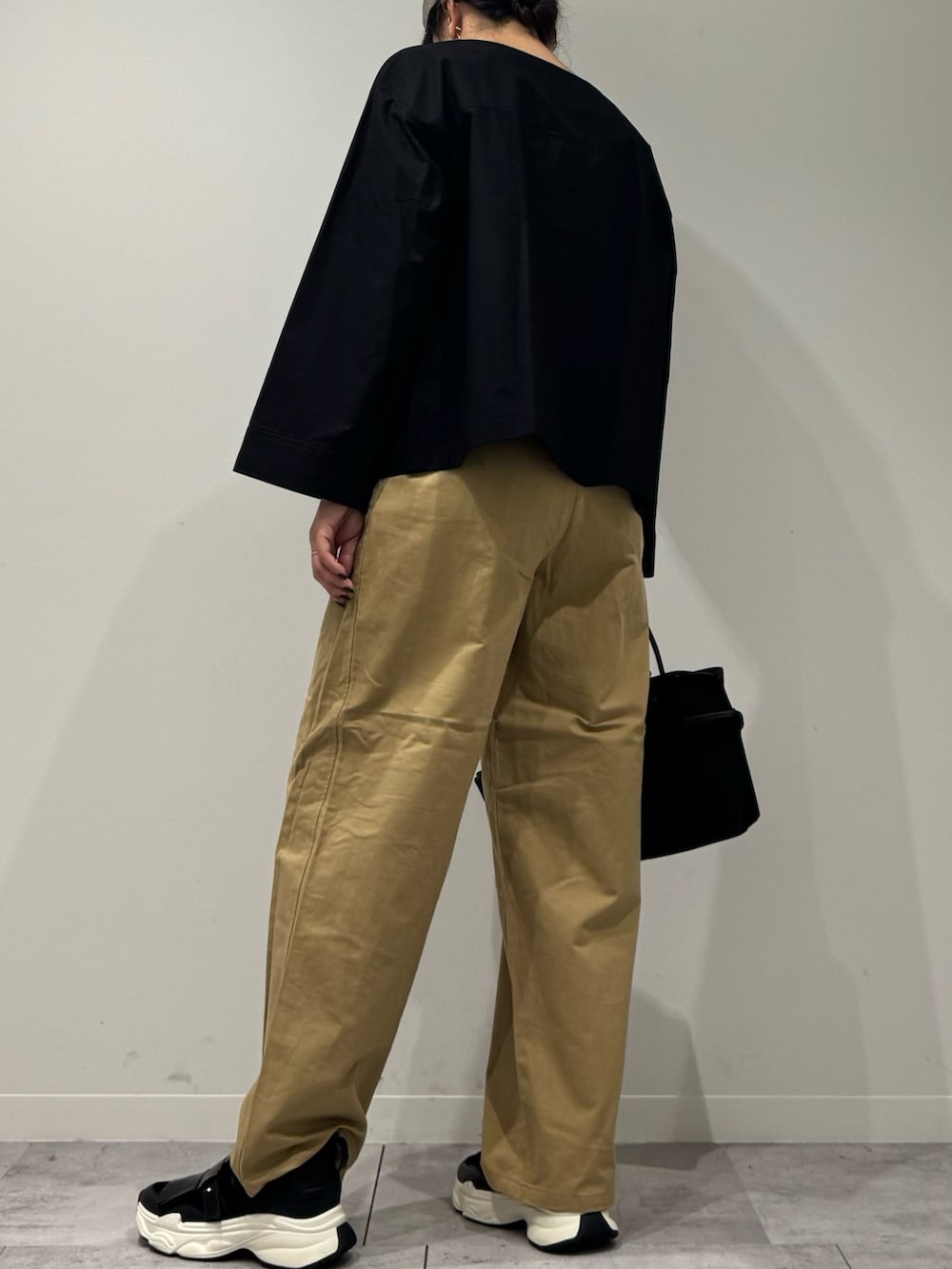 ブラック系のスニーカー、ベージュ系のチノパンツ、ブラック系のシャツ/ブラウスを着用したレディースの秋コーディネートの4枚目の写真