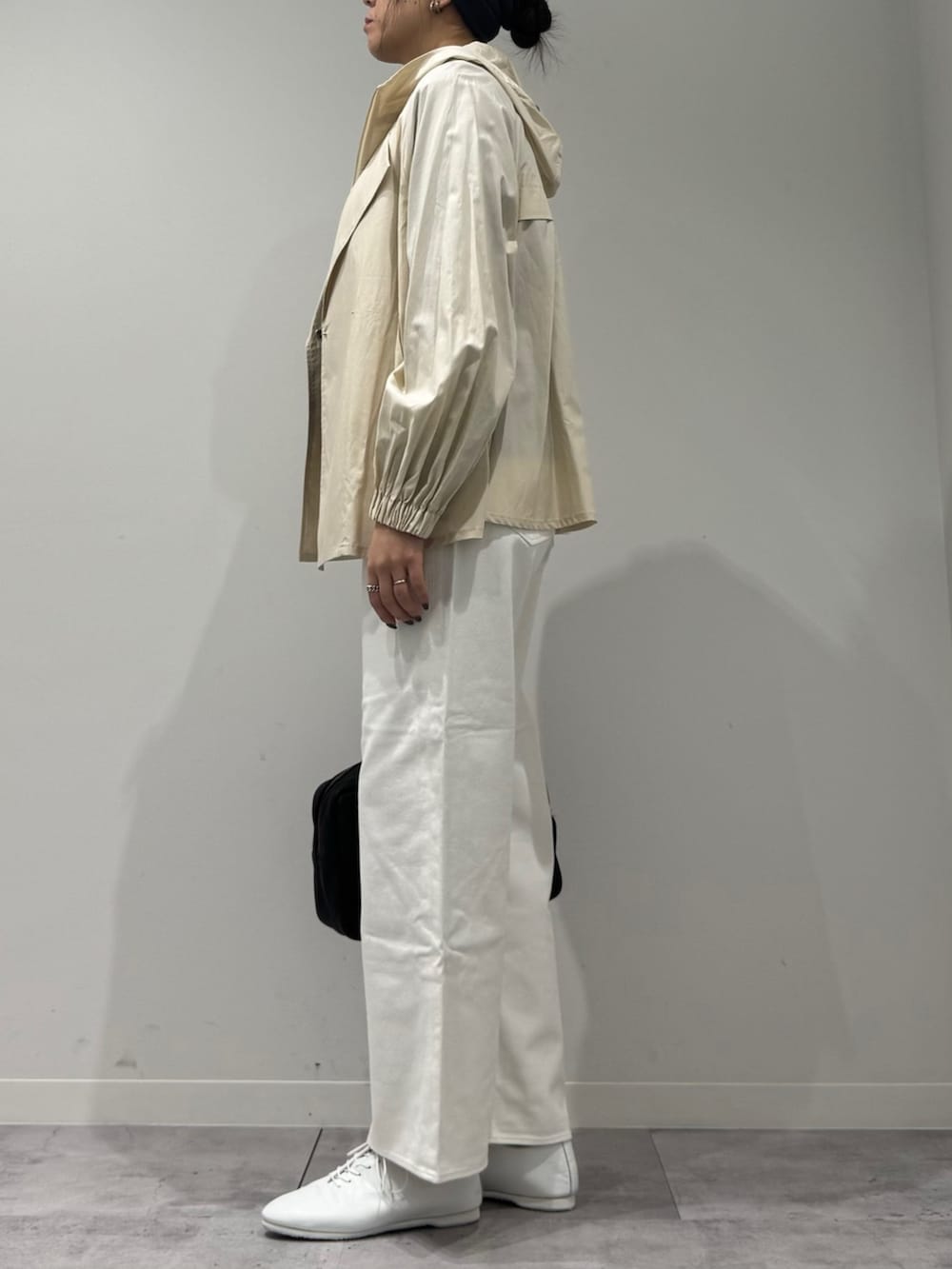 ブラック系のボストンバッグ、ホワイト系のトレンチコート、ホワイト系のデニムパンツを着用したレディースの冬コーディネートの5枚目の写真