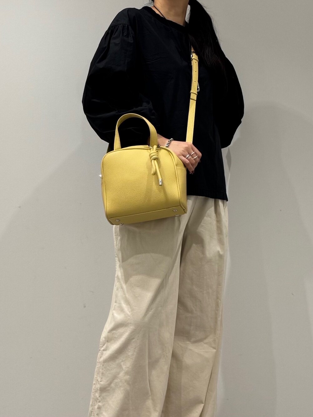 イエロー系のボストンバッグ、ブラック系のローファー、ブラック系のシャツ/ブラウスを着用したレディースの秋コーディネートの7枚目の写真