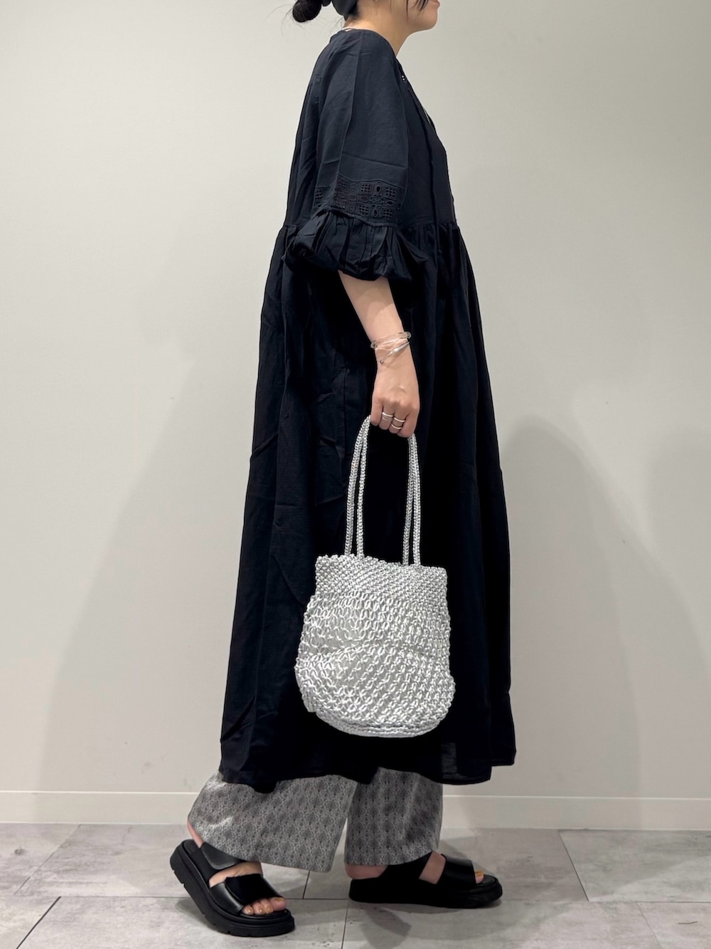 ブラック系のワンピース、シルバー系のかごバッグ、ブラック系のサンダルを着用したレディースの秋コーディネートの2枚目の写真