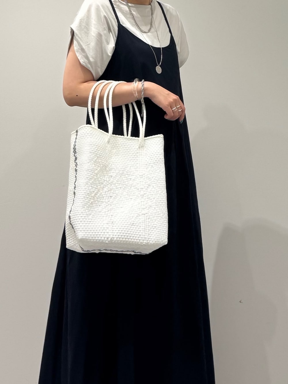ブラック系のワンピース、ホワイト系のかごバッグ、ブラック系のサンダルを着用したレディースの夏コーディネートの6枚目の写真