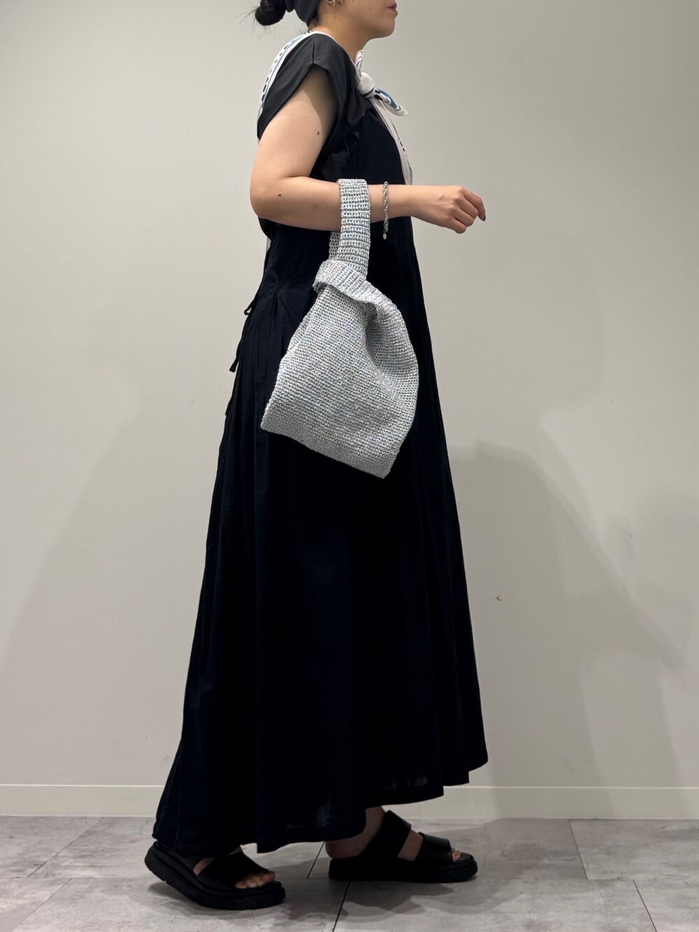 ブラック系のワンピース、シルバー系のかごバッグ、ブラック系のサンダルを着用したレディースの夏コーディネートの2枚目の写真