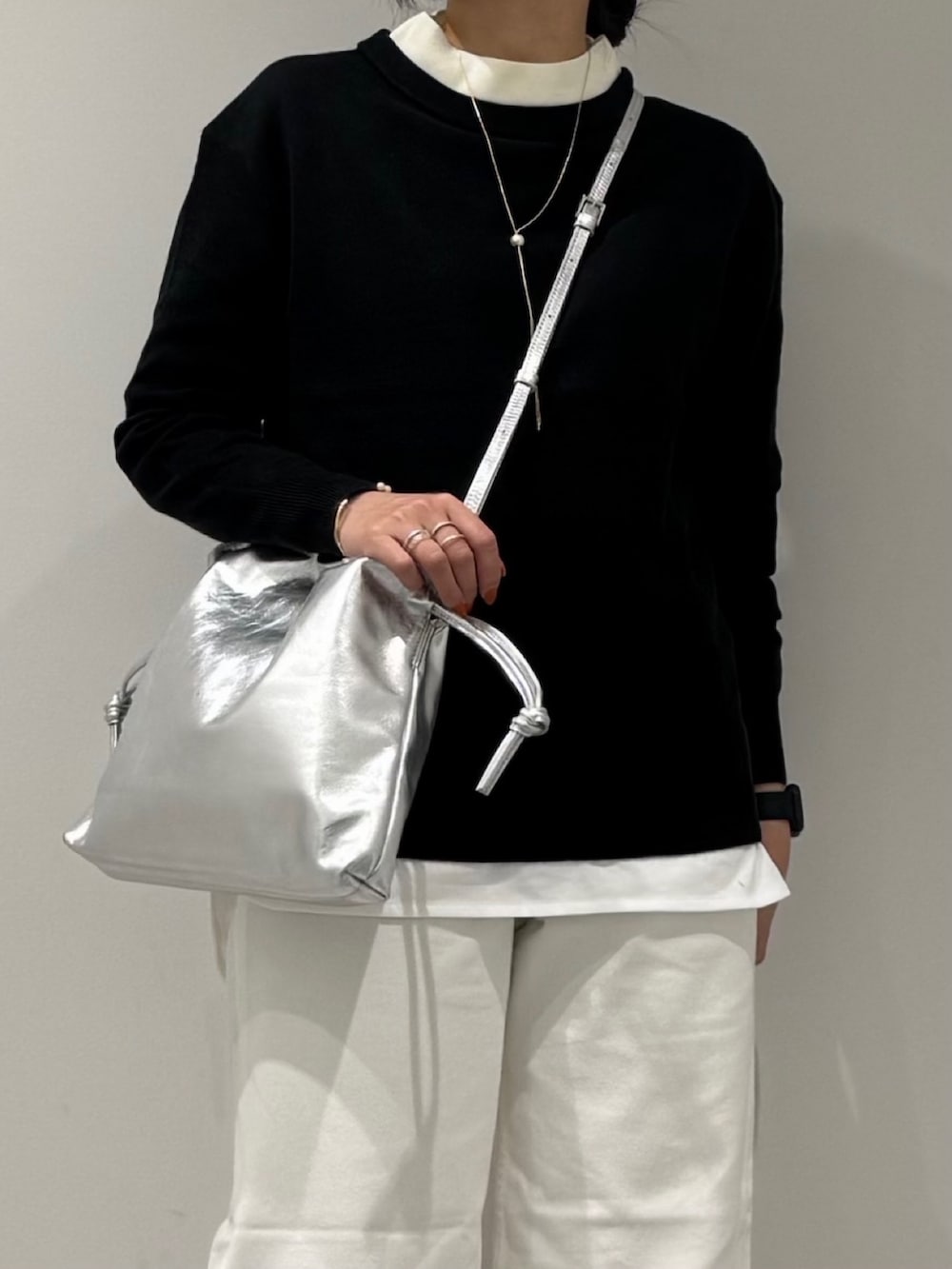 シルバー系のショルダーバッグ、ホワイト系のデニムパンツ、ブラック系のローファーを着用したレディースの冬コーディネートの7枚目の写真