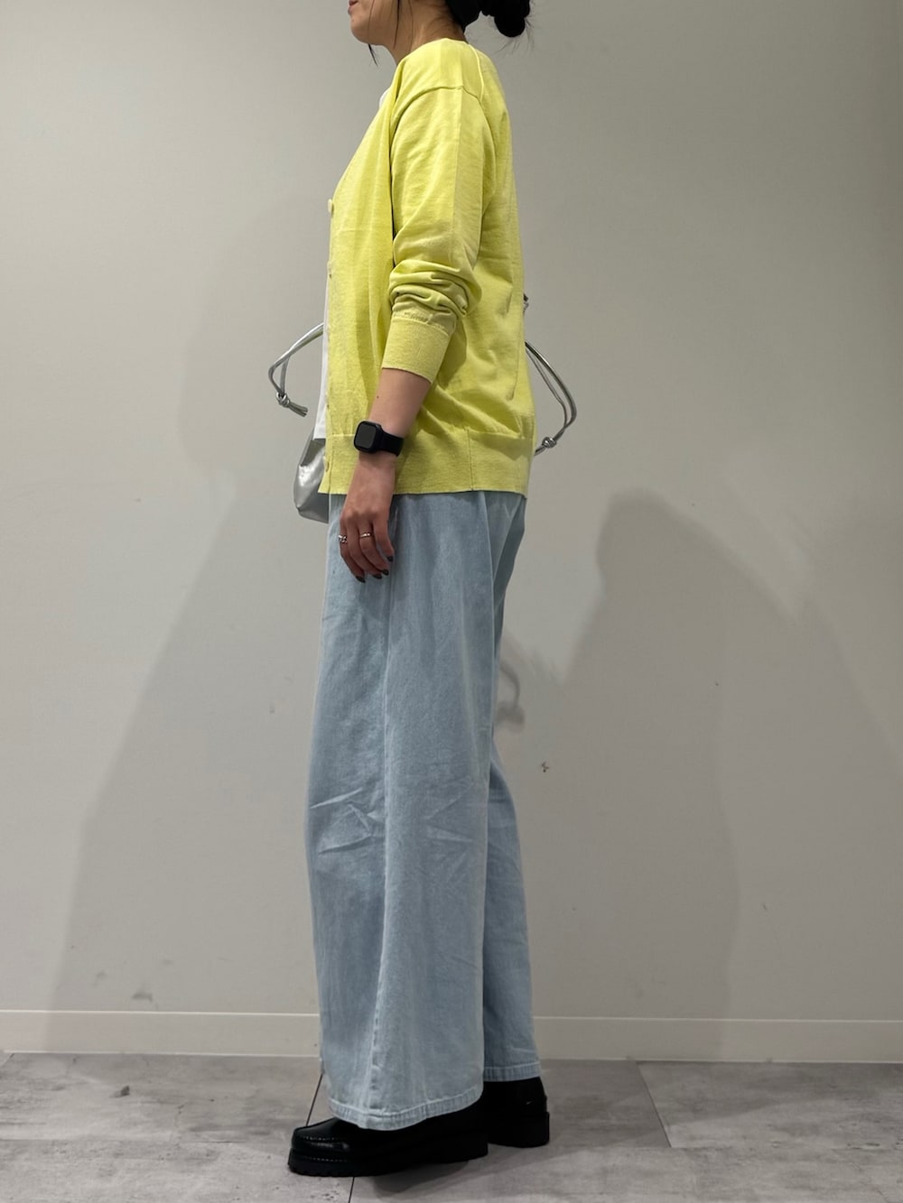 シルバー系のトートバッグ、ブラック系のローファー、ブルー系のデニムパンツを着用したレディースの春コーディネートの5枚目の写真