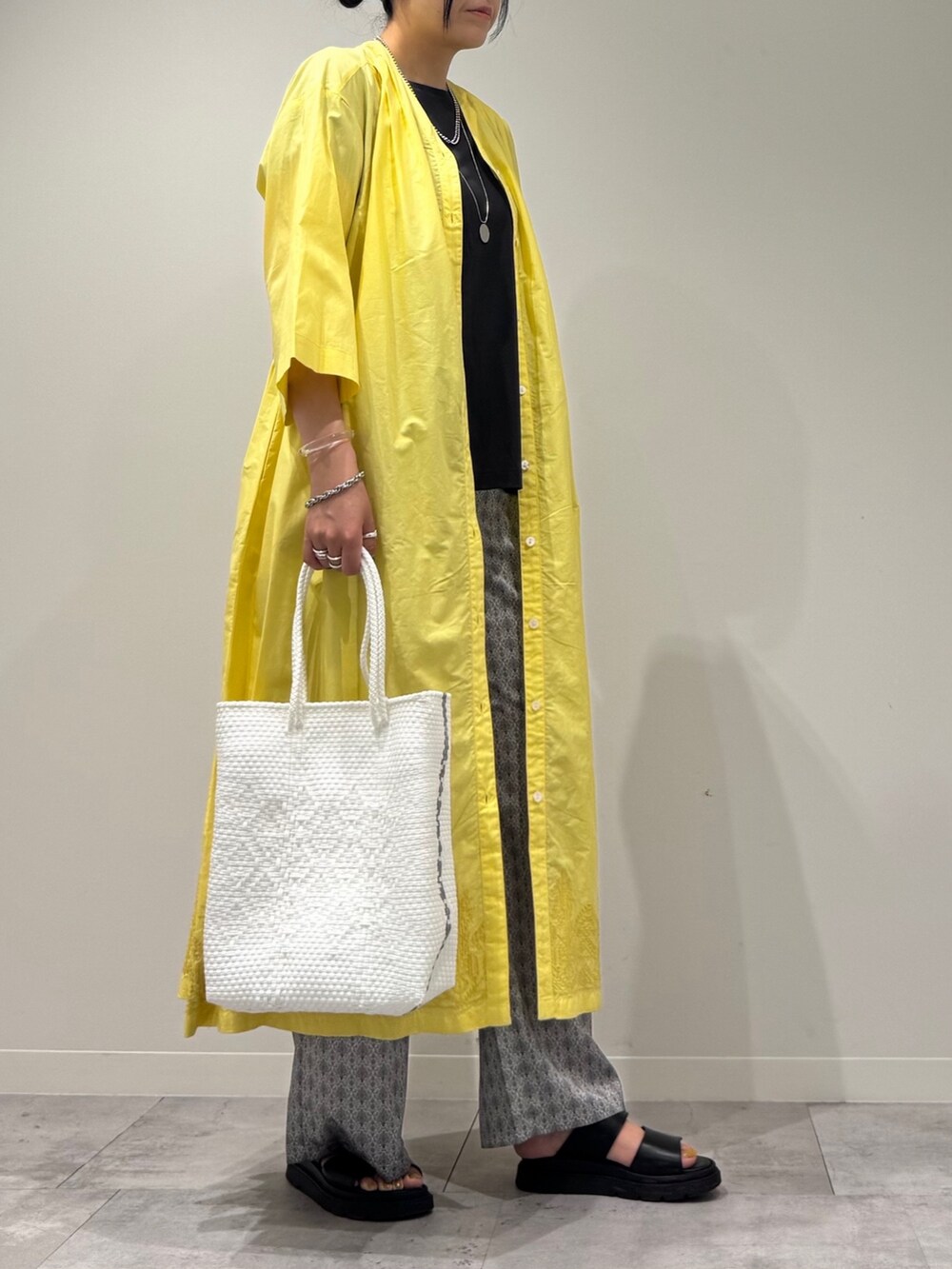 ホワイト系のかごバッグ、イエロー系のワンピース、ベージュ系のその他パンツを着用したレディースの夏コーディネートの2枚目の写真