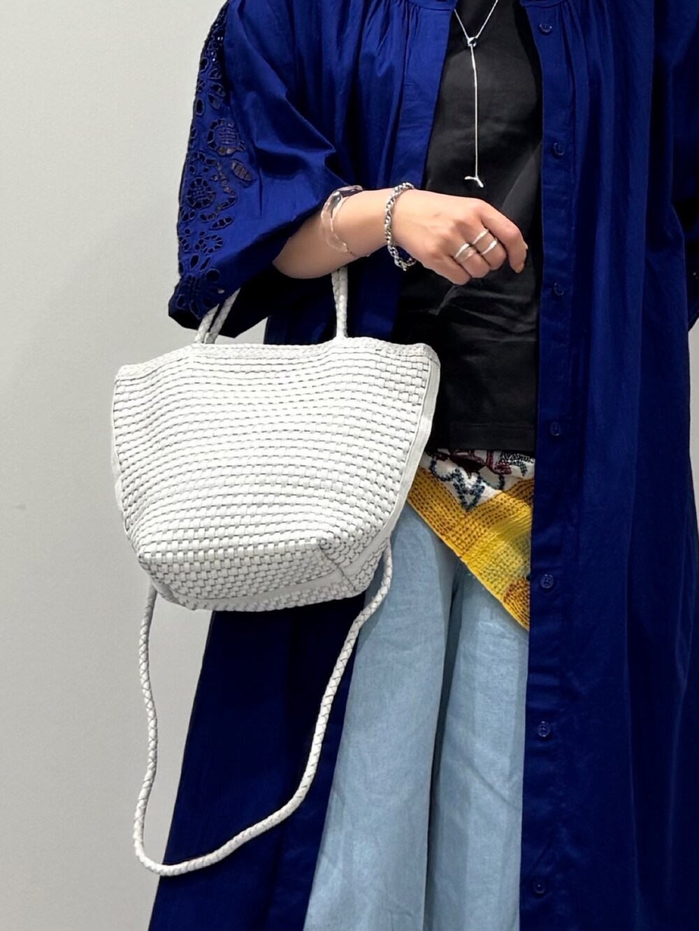 ホワイト系のトートバッグ、ブルー系のデニムパンツ、ブラック系のサンダルを着用したレディースの秋コーディネートの7枚目の写真