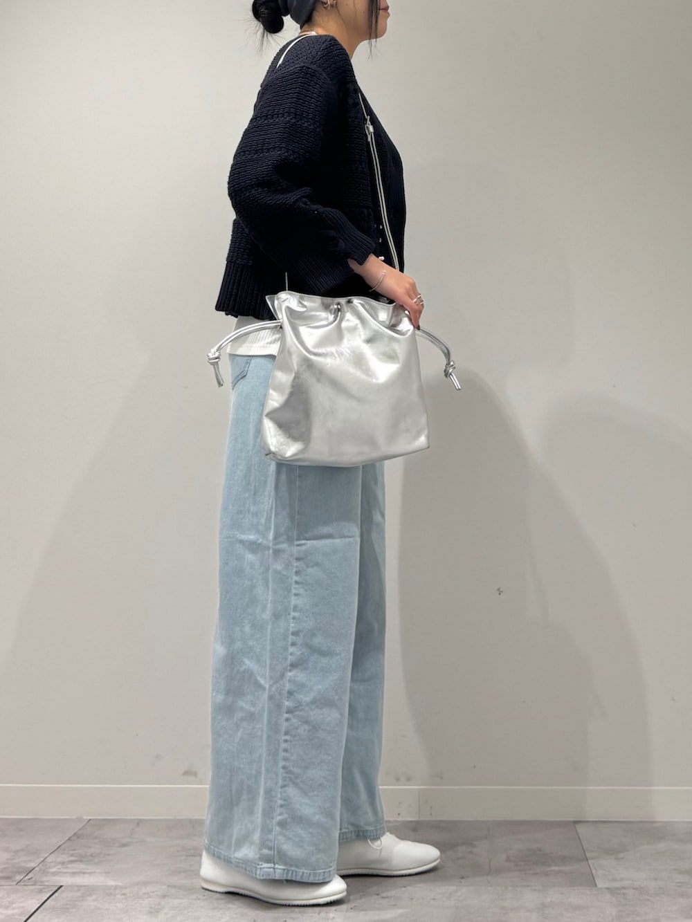 シルバー系のショルダーバッグ、ブルー系のデニムパンツ、ホワイト系のタンクトップを着用したレディースの春コーディネートの2枚目の写真