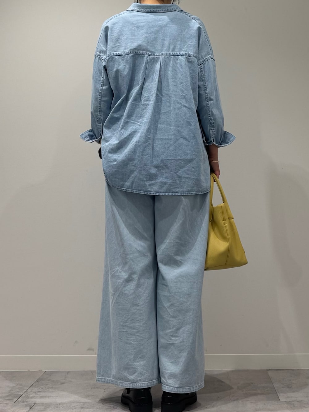 イエロー系のショルダーバッグ、ブルー系のデニムパンツ、ブラック系のローファーを着用したレディースの春コーディネートの3枚目の写真