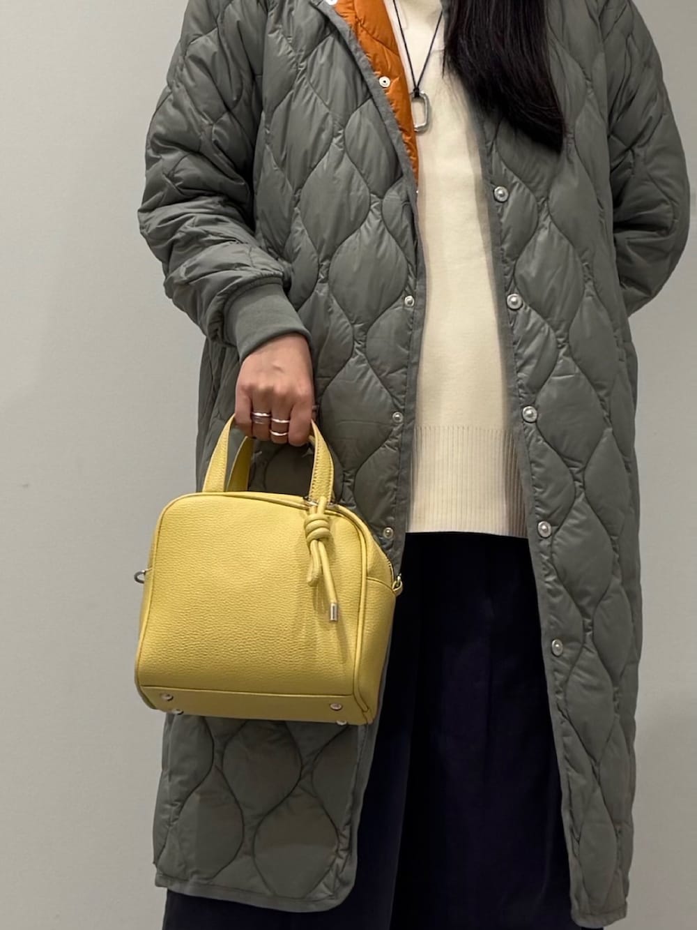 イエロー系のボストンバッグ、ブラック系のローファー、ホワイト系のベストを着用したレディースの秋コーディネートの8枚目の写真