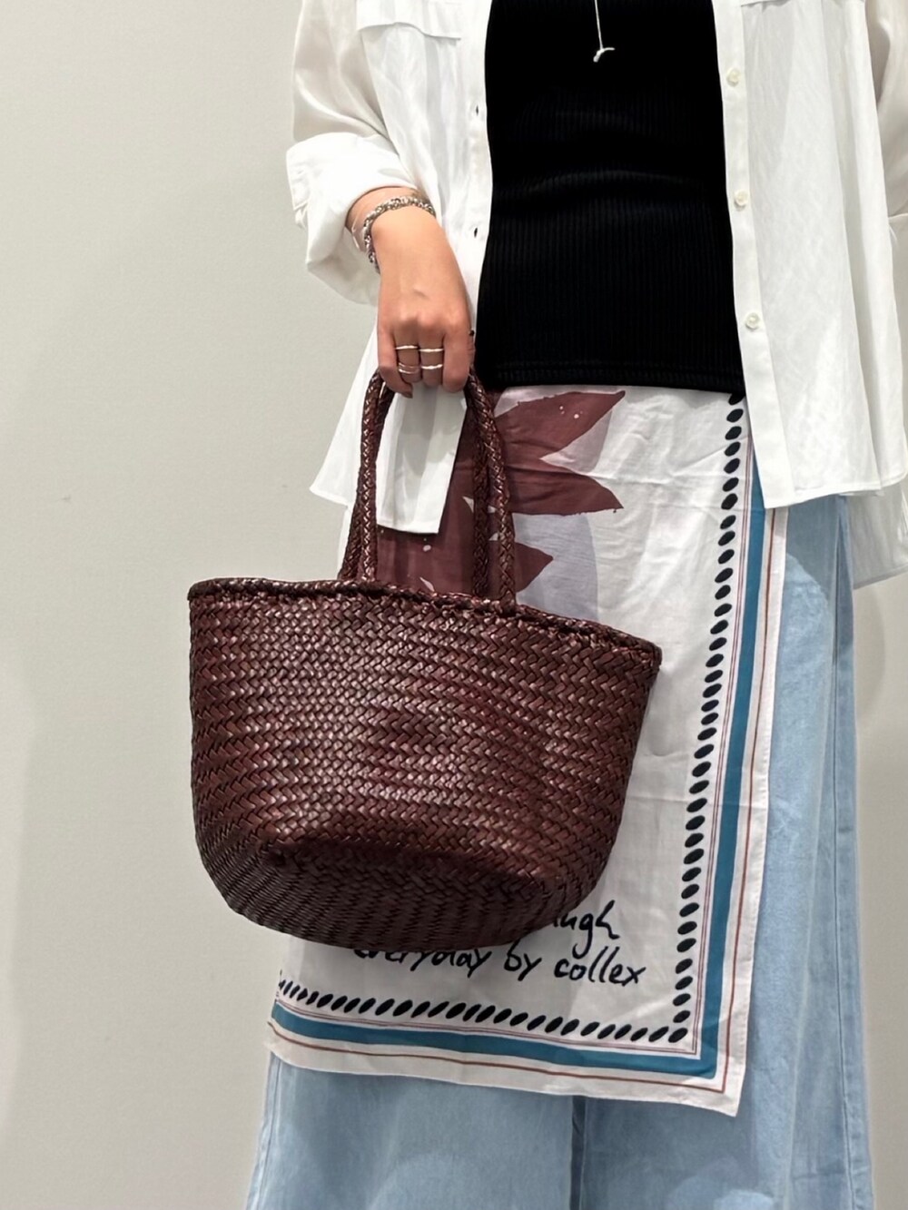 ブラウン系のトートバッグ、ブルー系のデニムパンツ、ブラック系のサンダルを着用したレディースの秋コーディネートの6枚目の写真