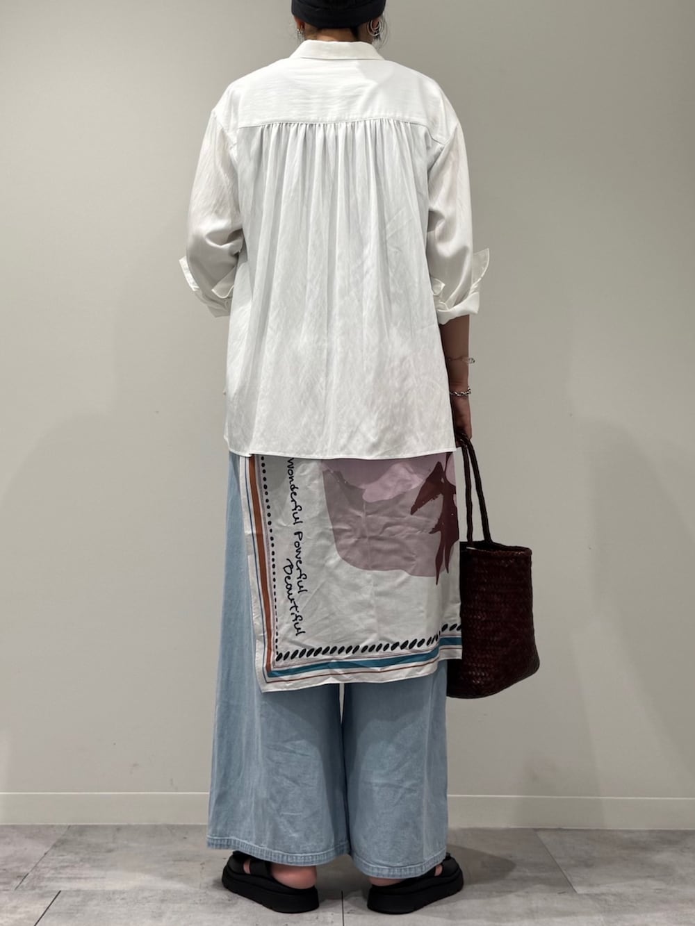 ブラウン系のトートバッグ、ブルー系のデニムパンツ、ブラック系のサンダルを着用したレディースの秋コーディネートの3枚目の写真