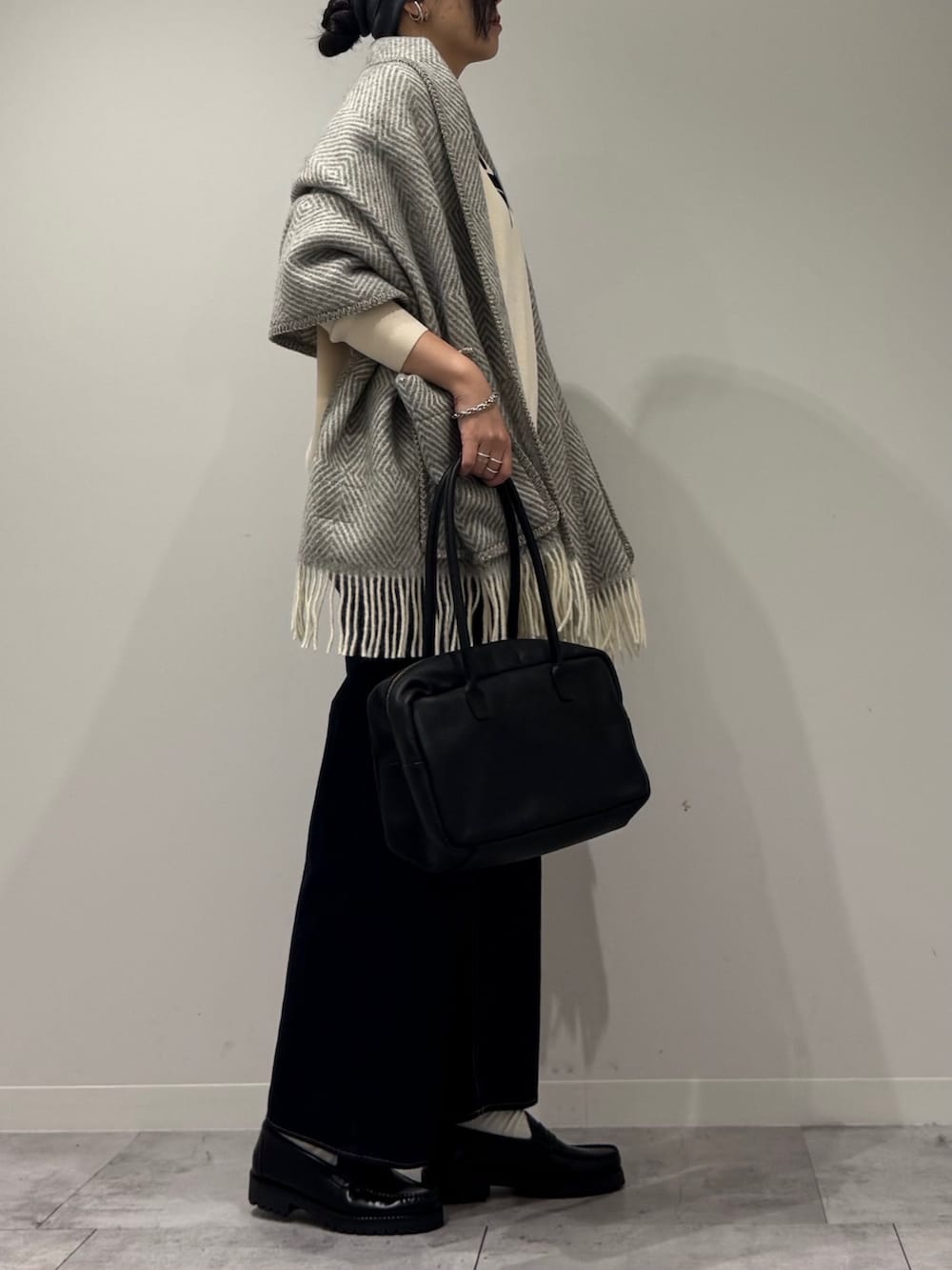 ブラック系のボストンバッグ、ブルー系のデニムパンツ、ブラック系のローファーを着用したレディースの冬コーディネートの2枚目の写真