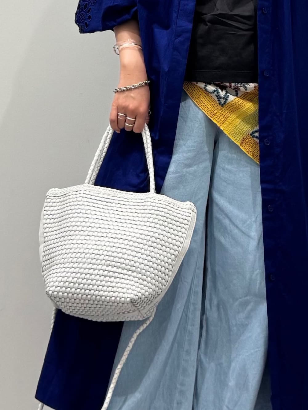 ホワイト系のトートバッグ、ブルー系のデニムパンツ、ブラック系のサンダルを着用したレディースの秋コーディネートの8枚目の写真