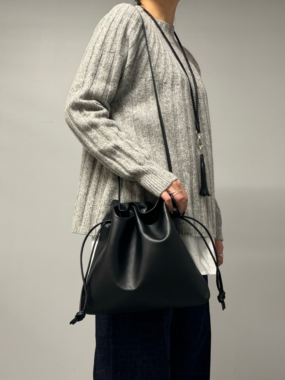 ブルー系のデニムパンツ、ブラック系のショルダーバッグ、グレー系のニット/セーターを着用したレディースの秋コーディネートの4枚目の写真