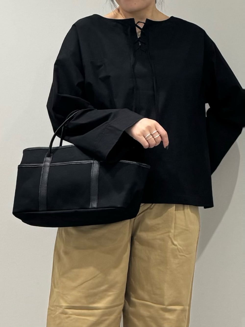 ブラック系のスニーカー、ベージュ系のチノパンツ、ブラック系のシャツ/ブラウスを着用したレディースの秋コーディネートの7枚目の写真