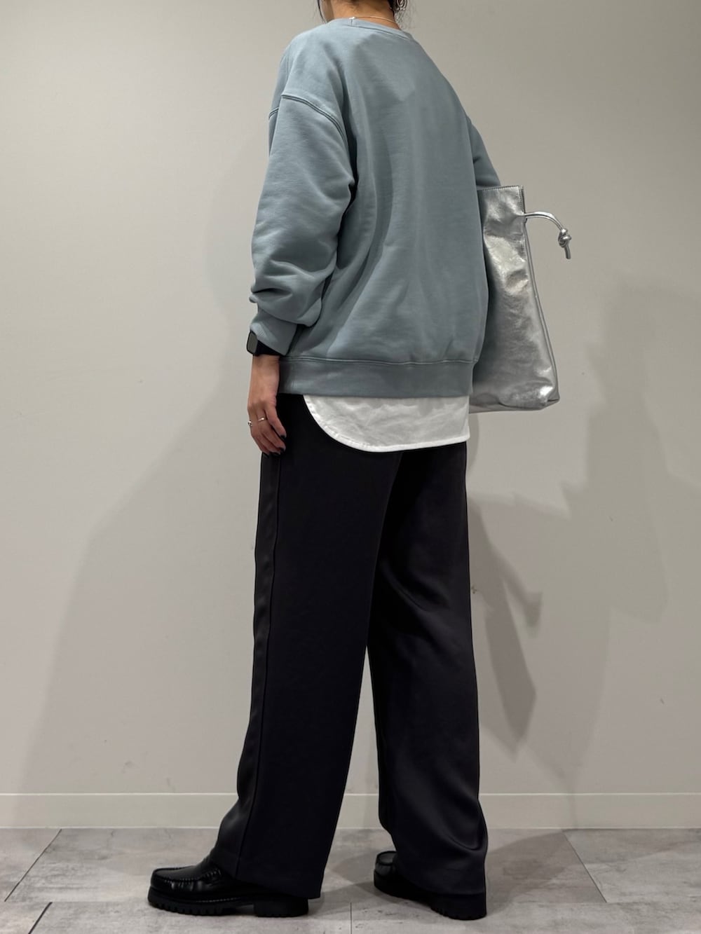 シルバー系のトートバッグ、ブルー系のスウェット、ホワイト系のTシャツ/カットソーを着用したレディースの冬コーディネートの4枚目の写真