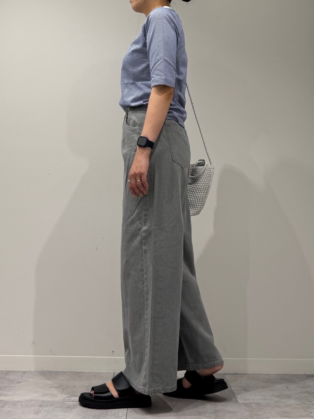 ホワイト系のトートバッグ、グレー系のデニムパンツ、ブラック系のサンダルを着用したレディースの夏コーディネートの4枚目の写真