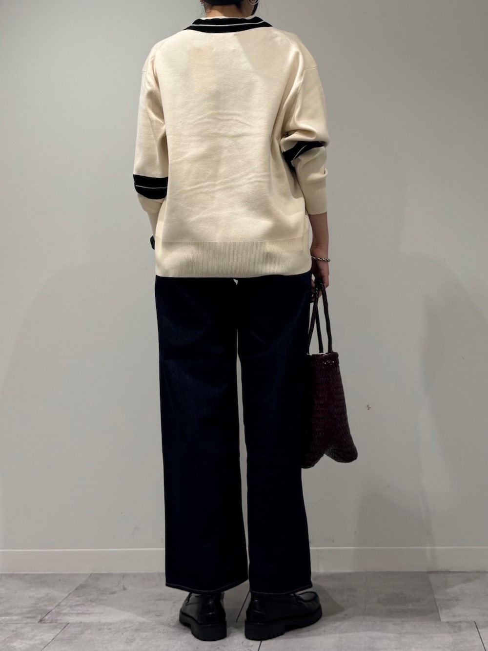 パープル系のトートバッグ、ブルー系のデニムパンツ、ブラック系のローファーを着用したレディースの冬コーディネートの4枚目の写真