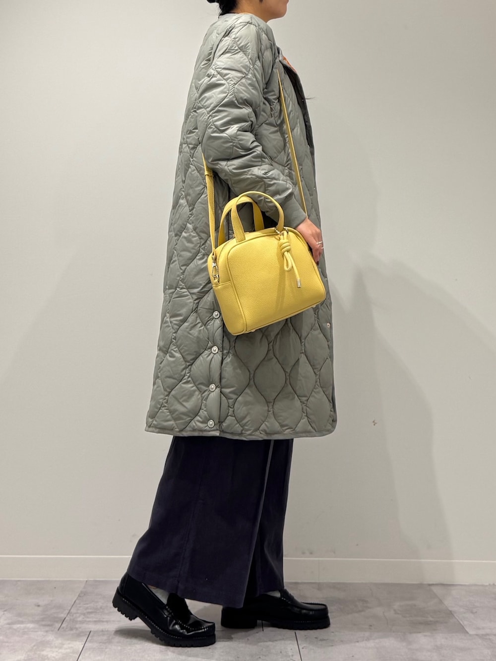 イエロー系のボストンバッグ、ブラック系のローファー、ホワイト系のベストを着用したレディースの秋コーディネートの3枚目の写真