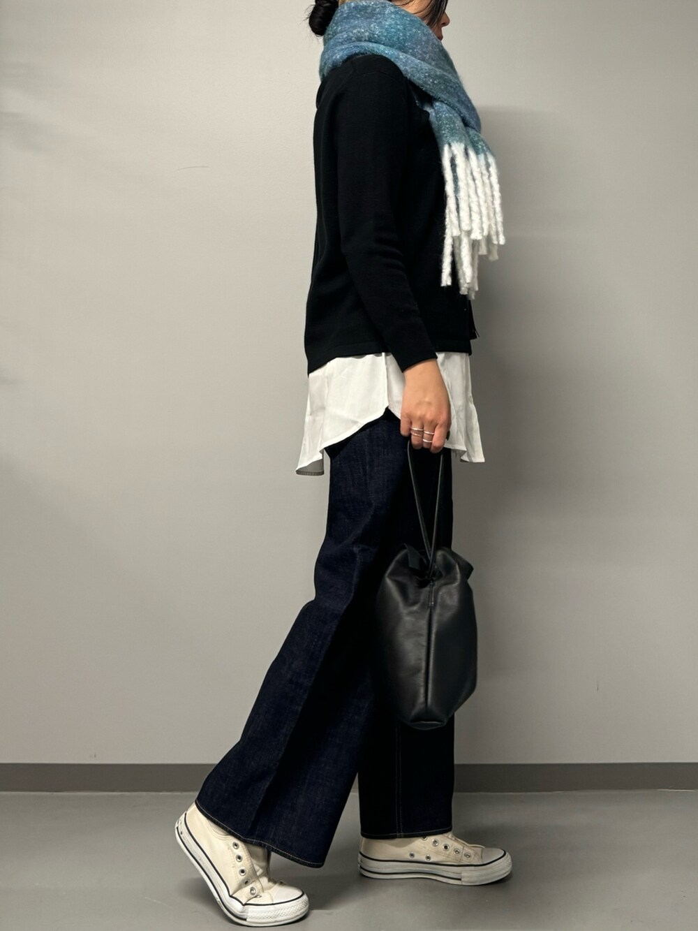 ブラック系のニット/セーター、ブルー系のデニムパンツ、ブラック系のショルダーバッグを着用したレディースの秋コーディネートの5枚目の写真