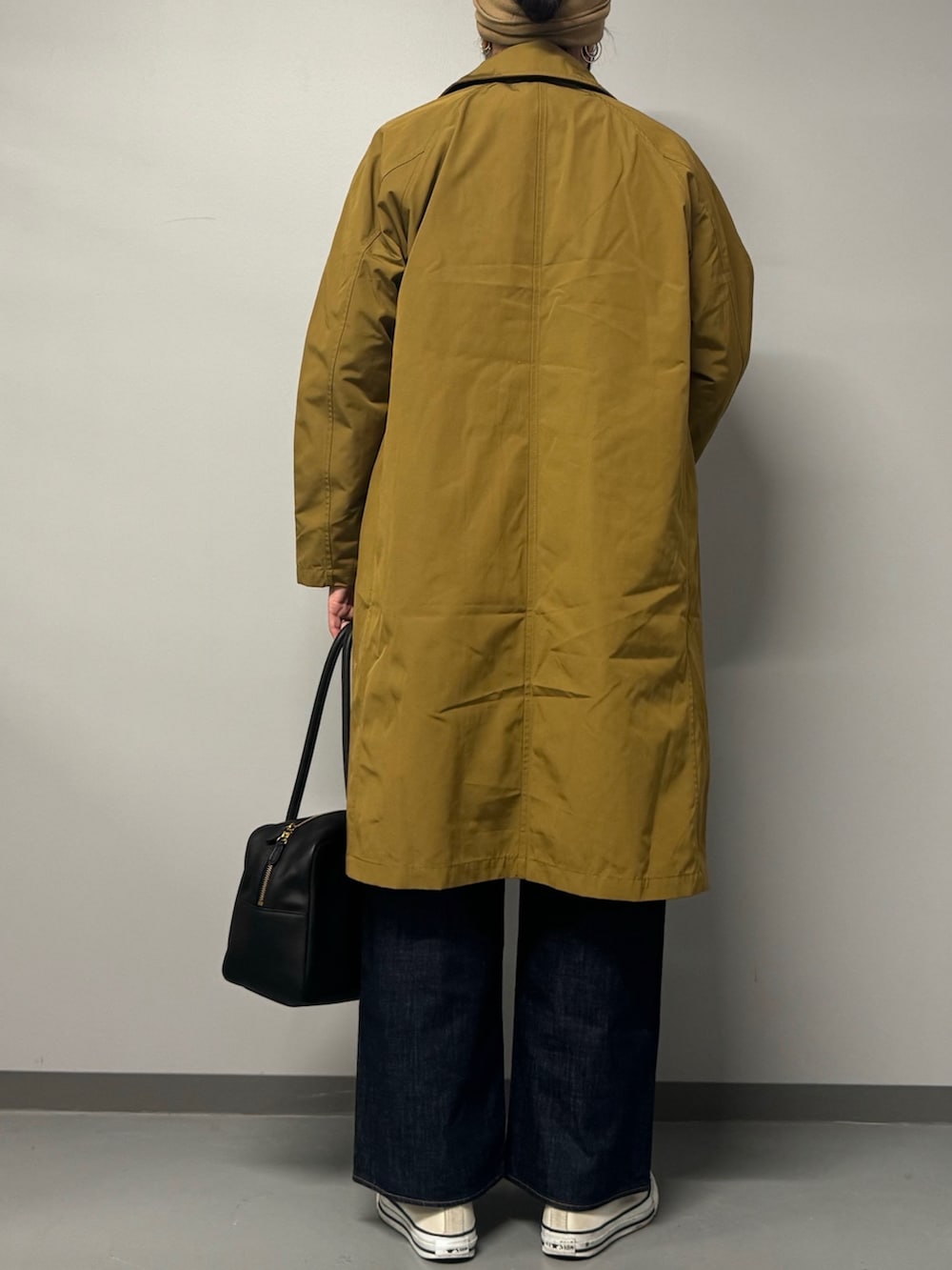 ベージュ系のダウンジャケット/コート、ブラック系のボストンバッグ、ブルー系のデニムパンツを着用したレディースの秋コーディネートの2枚目の写真