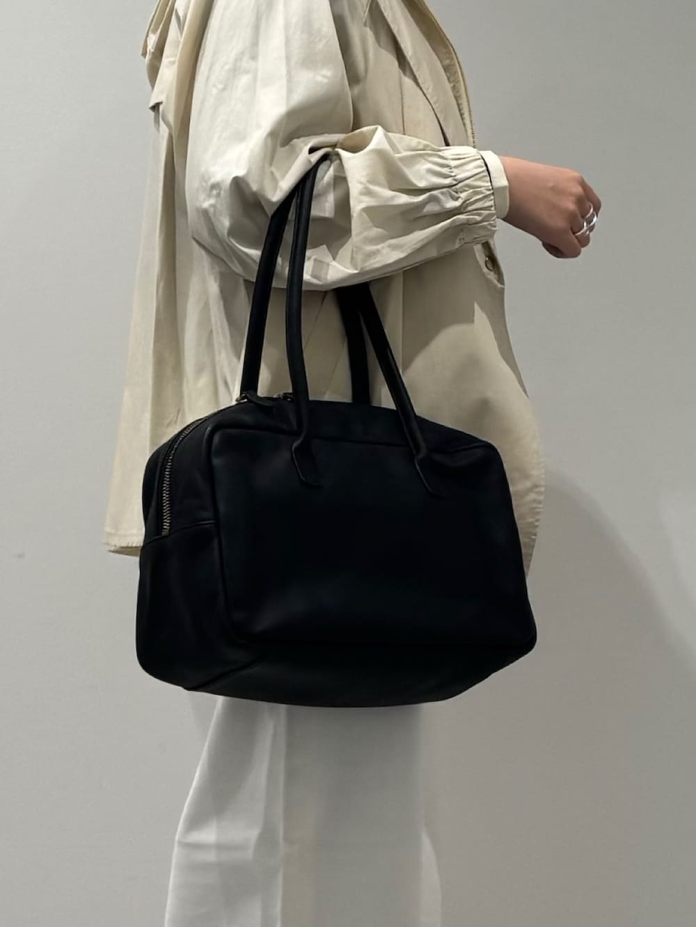 ブラック系のボストンバッグ、ホワイト系のトレンチコート、ホワイト系のデニムパンツを着用したレディースの冬コーディネートの7枚目の写真